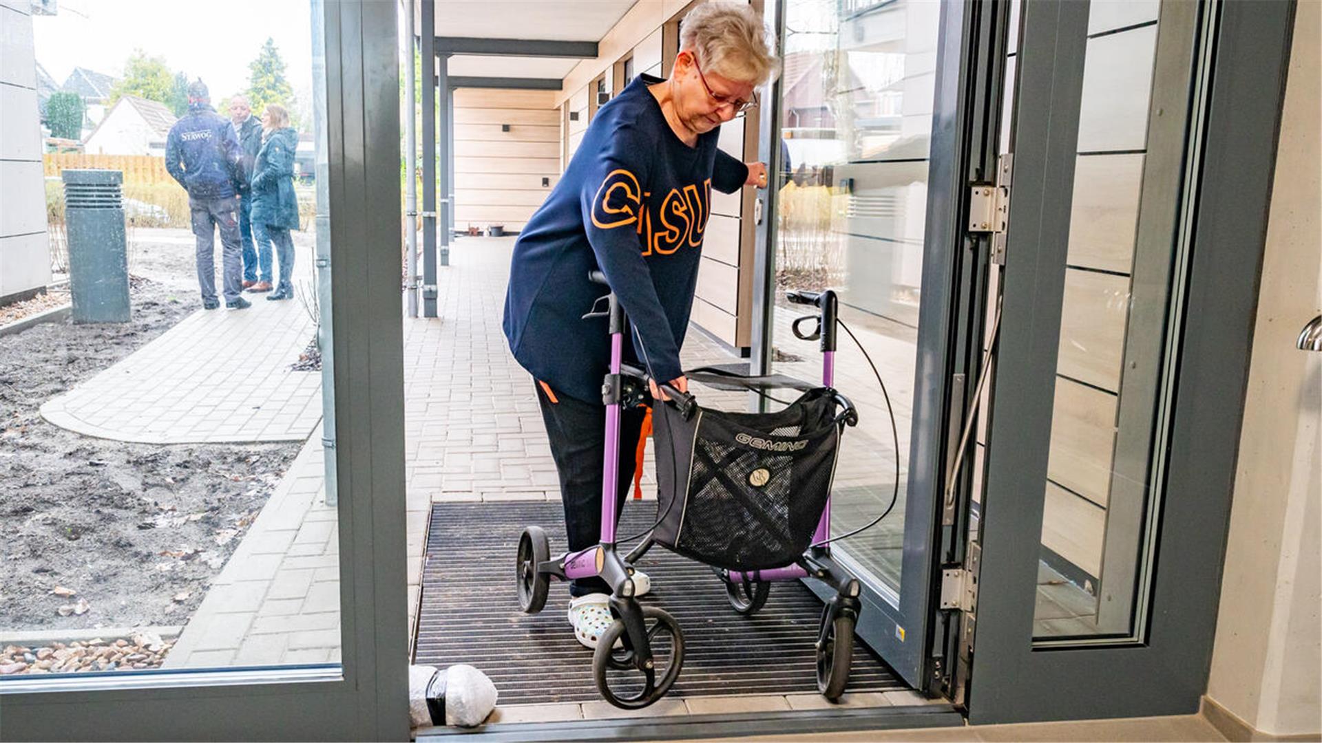 Der Stäwog-Neubau an der Isarstraße in Bremerhaven-Surheide ist noch nicht komplett bezogen, darum stoßen Mieter mit Rollstuhl oder Rollator - wie hier Karin Coordes - derzeit noch auf „Barrieren“ wie diese nicht automatische Eingangstür.