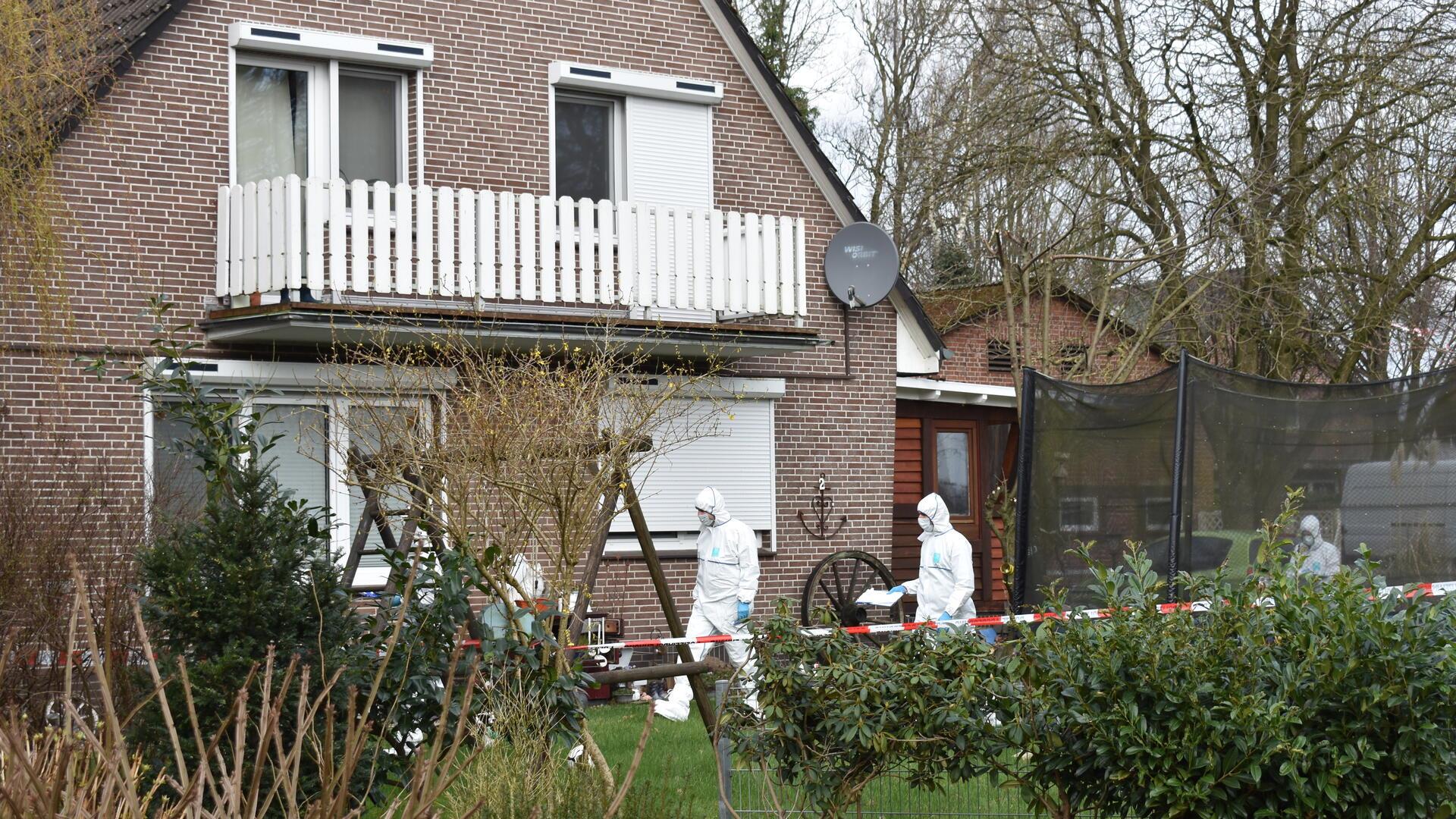 Ein Haus mit einem weißen Balkon, vor dem Männer in weißen Overalls zu sehen sind.