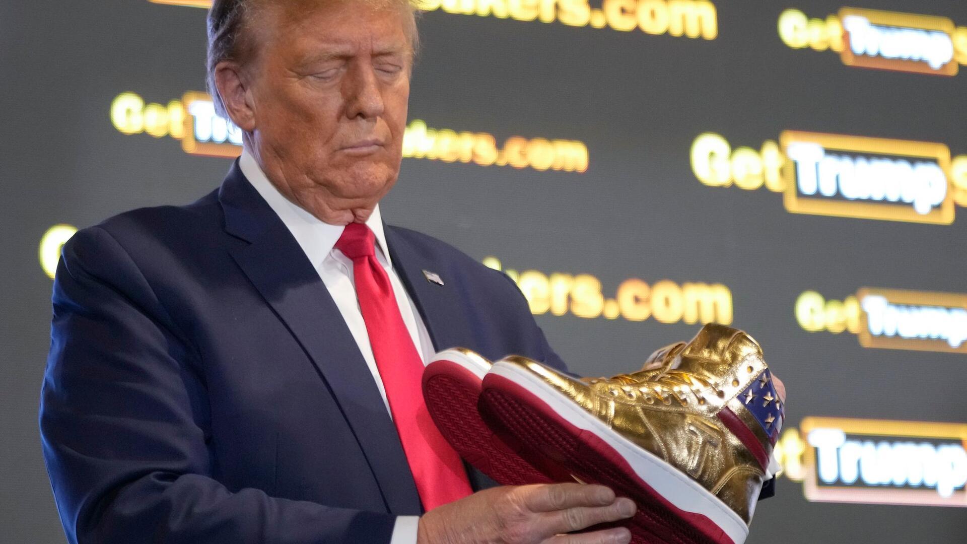 Der ehemalige US-Präsident Donald Trump hält goldene Trump-Sneakers auf der Sneaker Con Philadelphia, einer Veranstaltung für Sneakersammler.