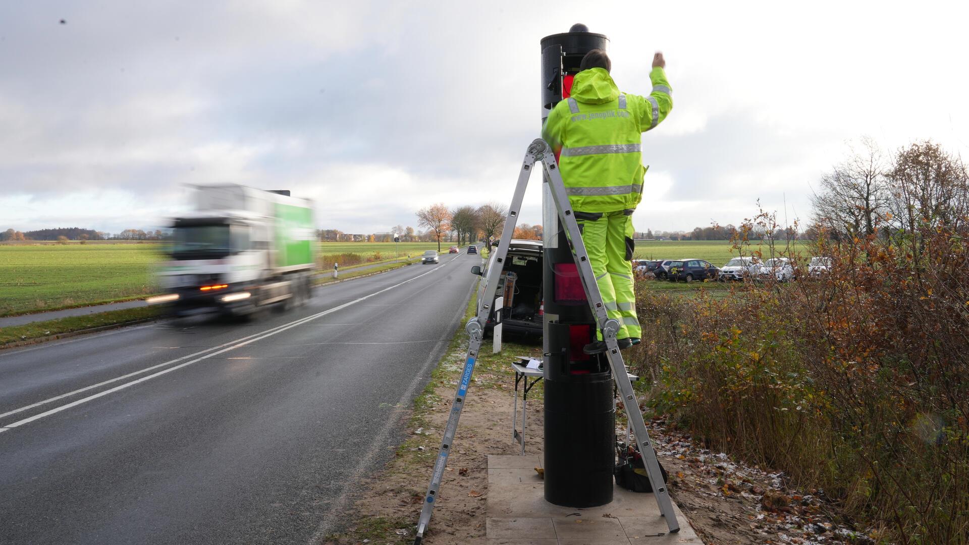 Ein Mann baut einen Blitzer an der L119 bei Neuenwalde auf.