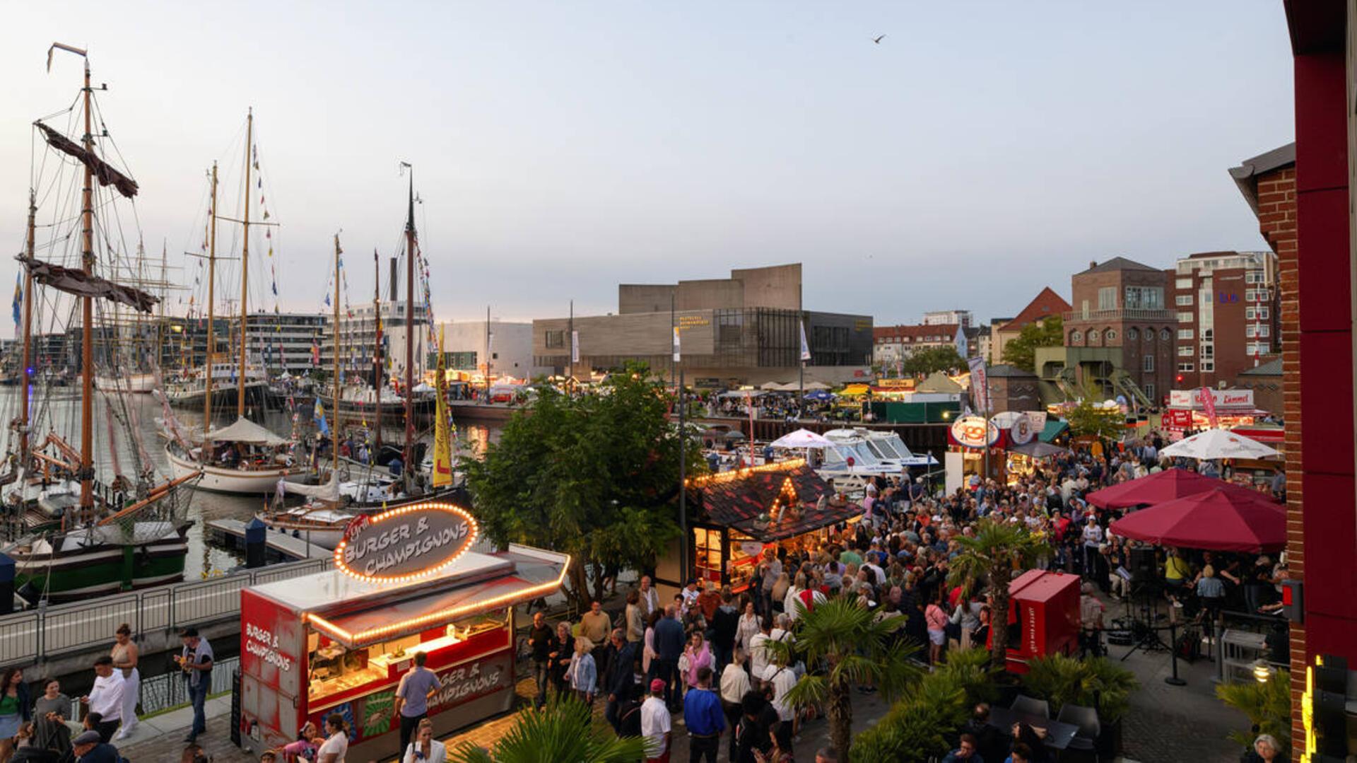 Ein Hafen, an dem sich viele Menschen tummeln. 