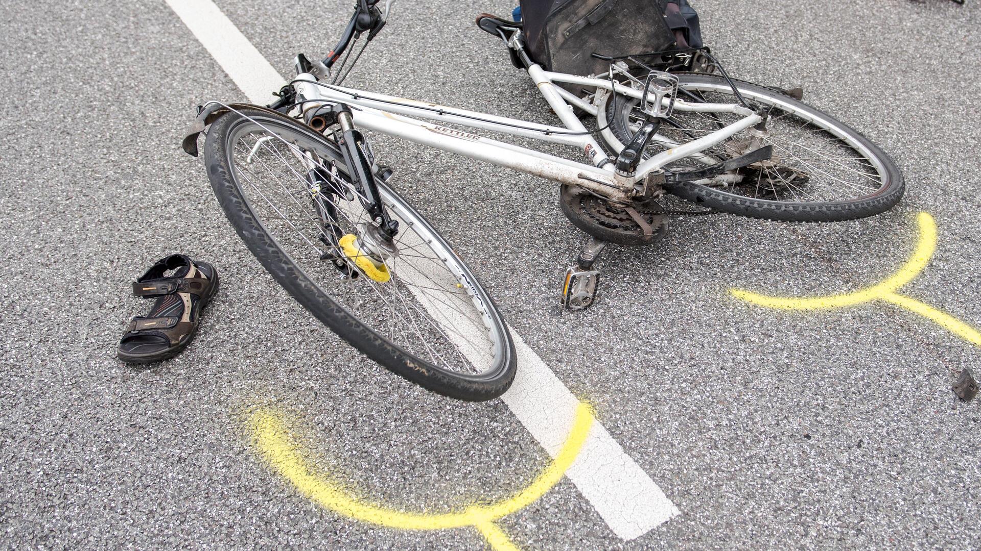 Ein Fahrrad liegt auf einer Straße und um die Reifen sind gelbe Markierungen gemalt.