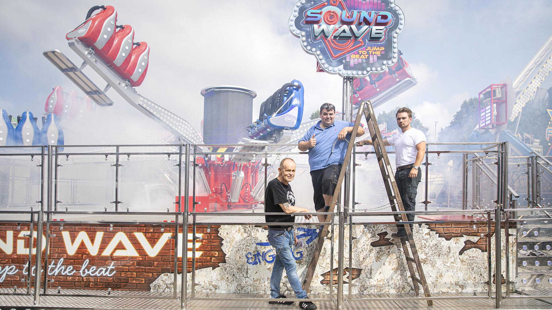 Die Betreiber des Soundwave auf dem Freimarkt 2024: Vater Danny Schwerin, Sohn Anthony Schwerin und Veranstalter Uwe Zander nehmen ihr Karussell in Betrieb.