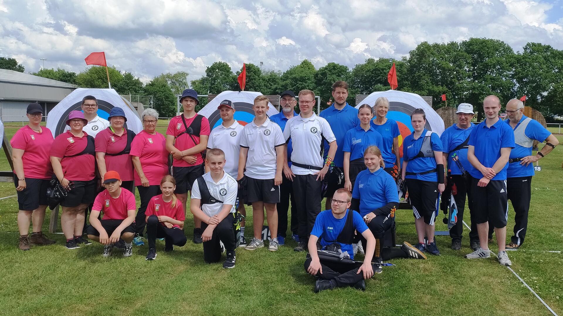 Viele Männer und Frauen in blauen, weißen und roten poloshirts stehen auf dem Rasen.