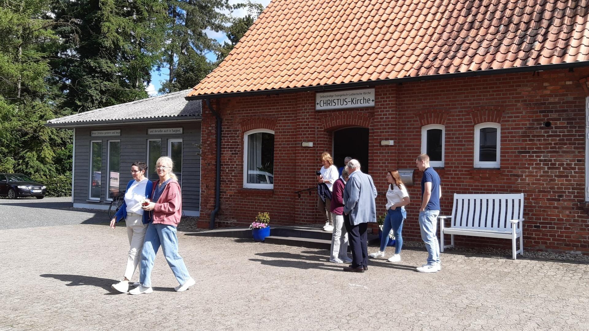 Das Foto zeigt Leute vor der Kirche der Christus-Gemeinde. 