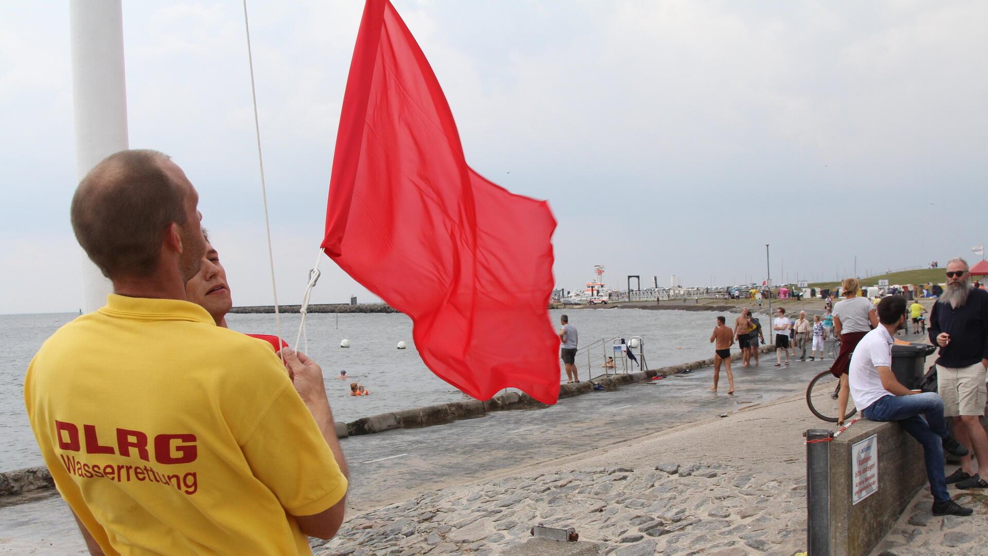Ein Mann hisst eine rote Fahne