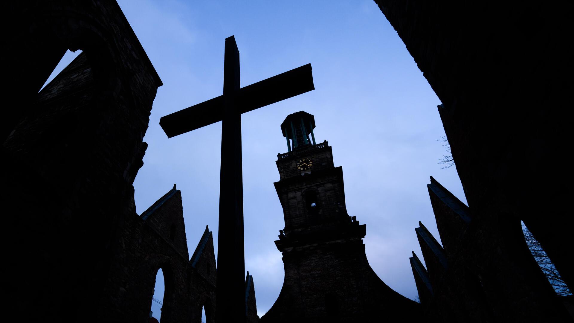 Ein großes Kreuz steht vor einer Kirche.