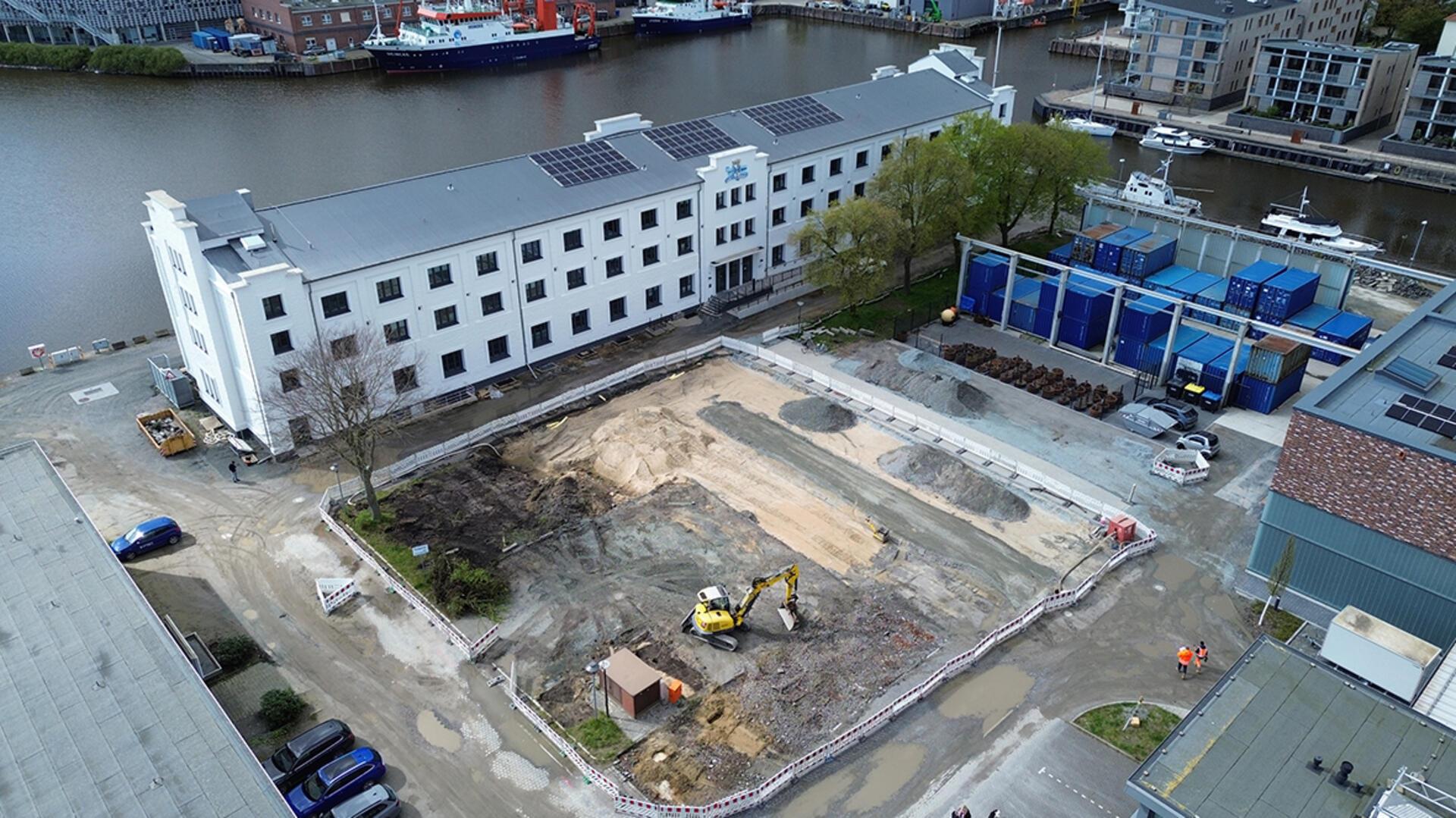 Luftfoto einer Baustelle mit einem Bagger zwischen mehreren Gebäuden des AWI-Campus