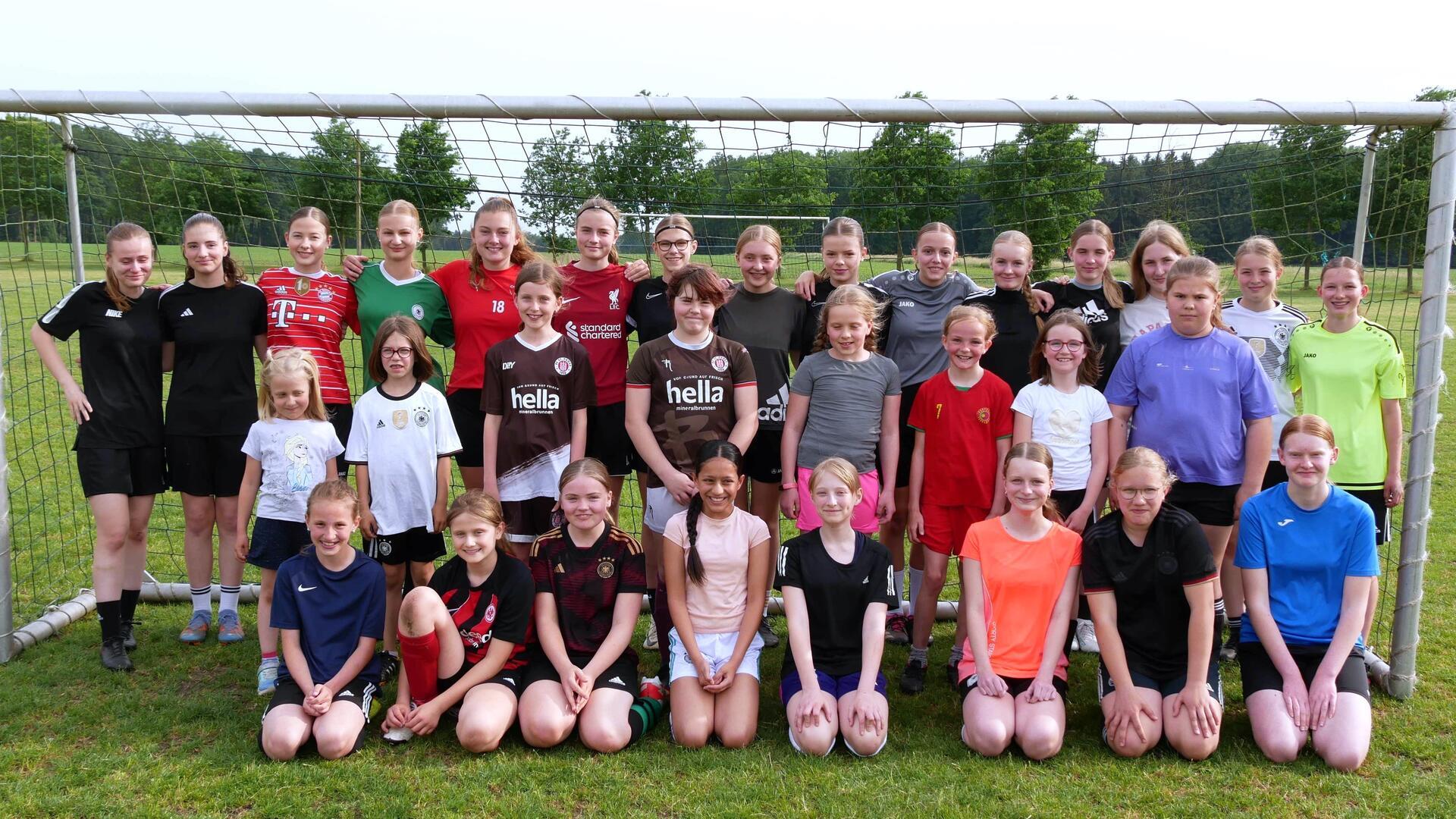 Sehr viele Mädchen stehen in einem Fußballtor.