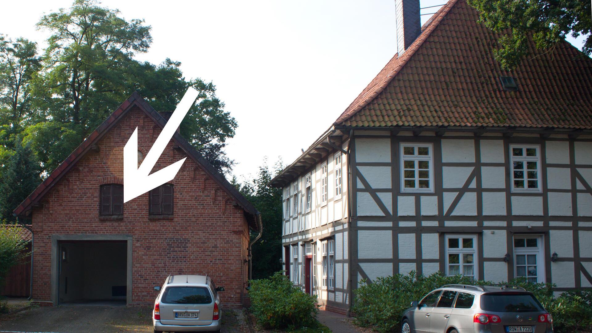 Auf dem Bild sind ein Haus und eine Garage zu sehen. Das Garagentor ist mit einem Pfeil versehen. 