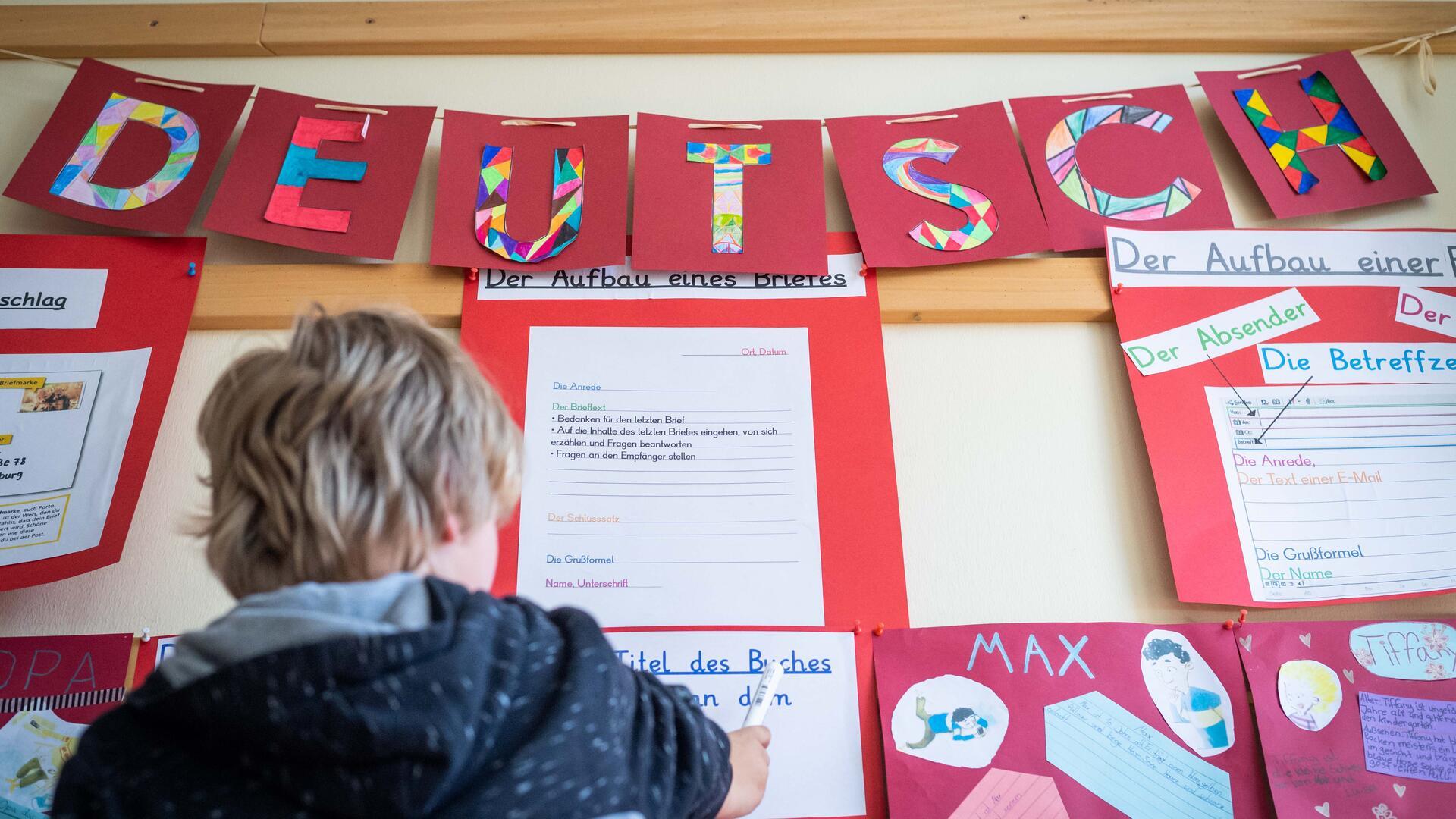 Ein Schüler schreibt in der Klasse an eine Wand.