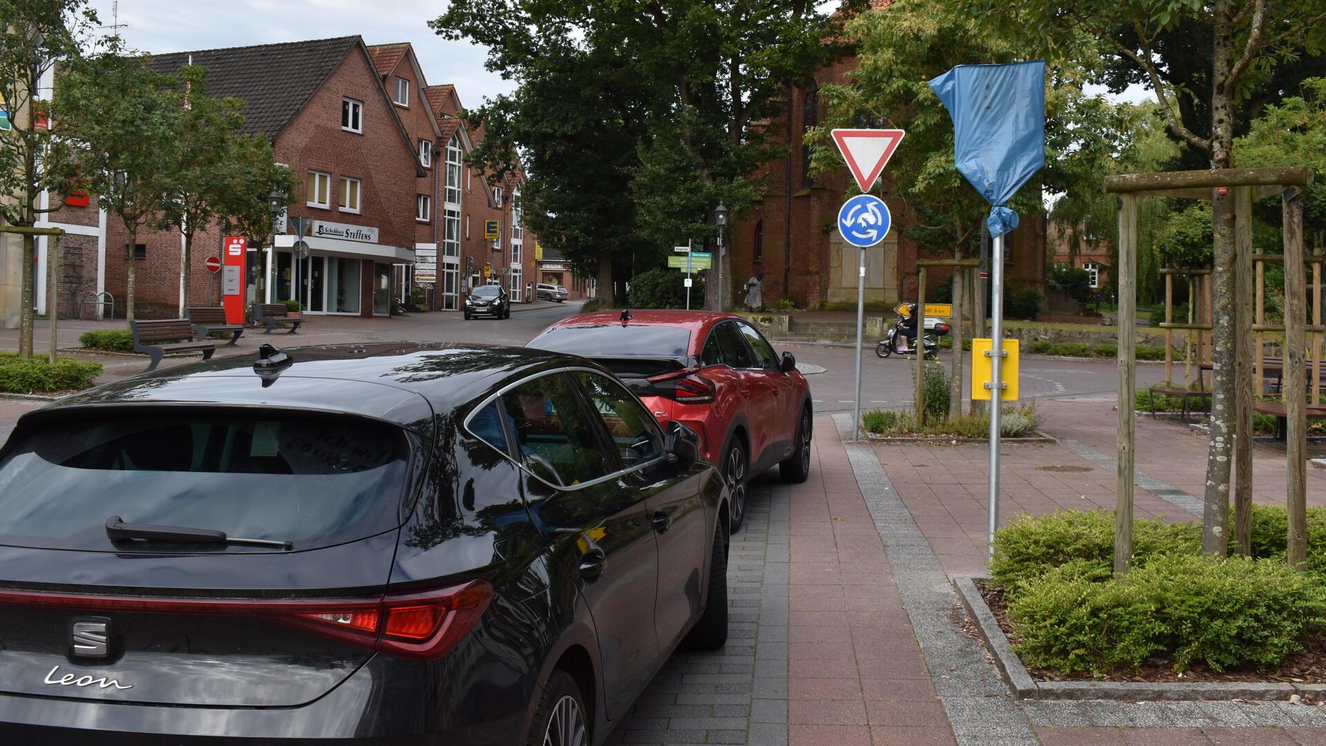 Zwei Autos vor einer verhüllten Bushaltestelle.