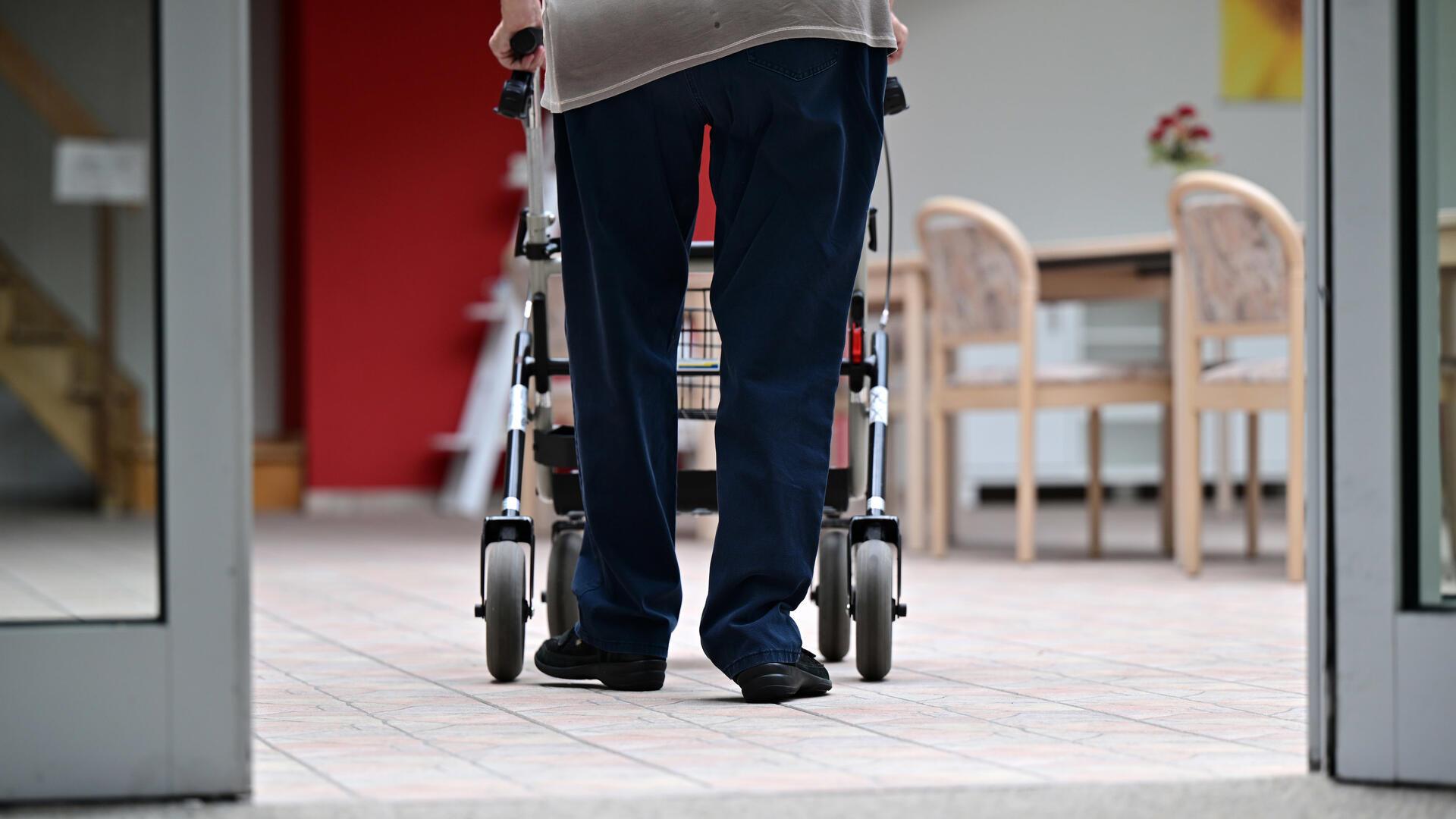 Ein Bewohner geht mit dem Rollator durch ein Pflegeheim. 