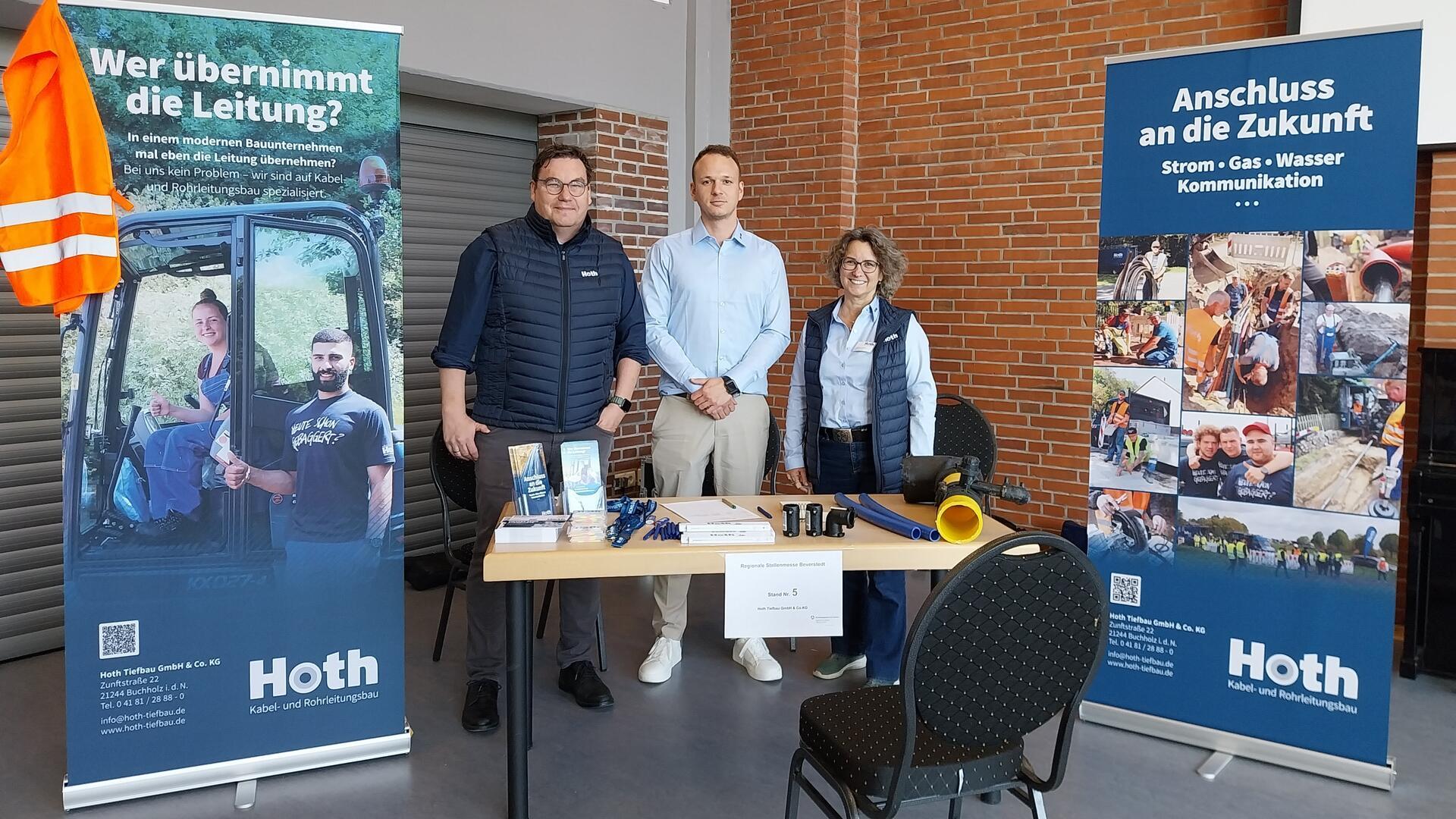 Drei Menschen bei einer Messe an einem Stand