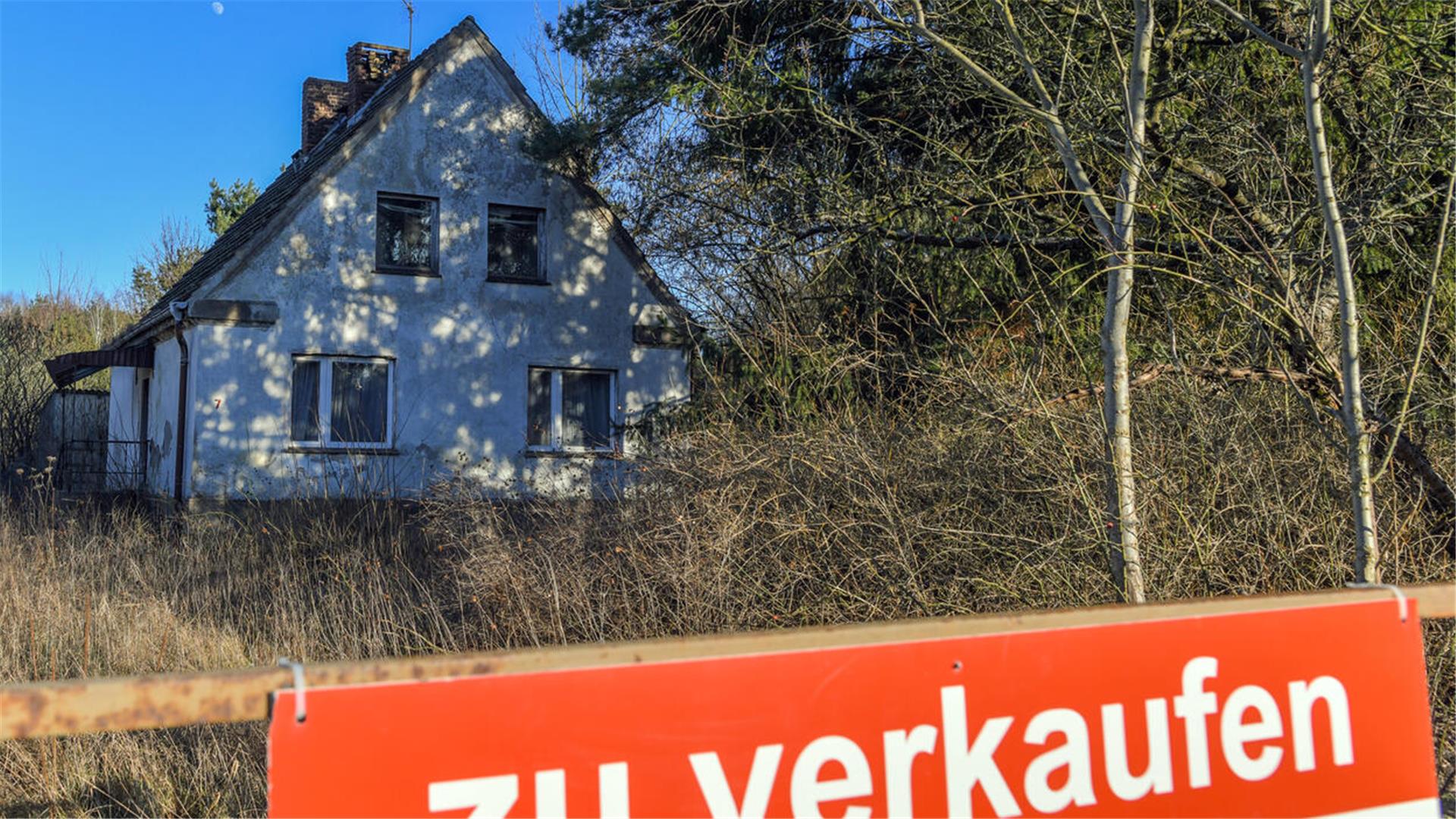 Ein Schild mit der Aufschrift «zu verkaufen» steht auf einem Grundstück mit einem Einfamilienhaus. 