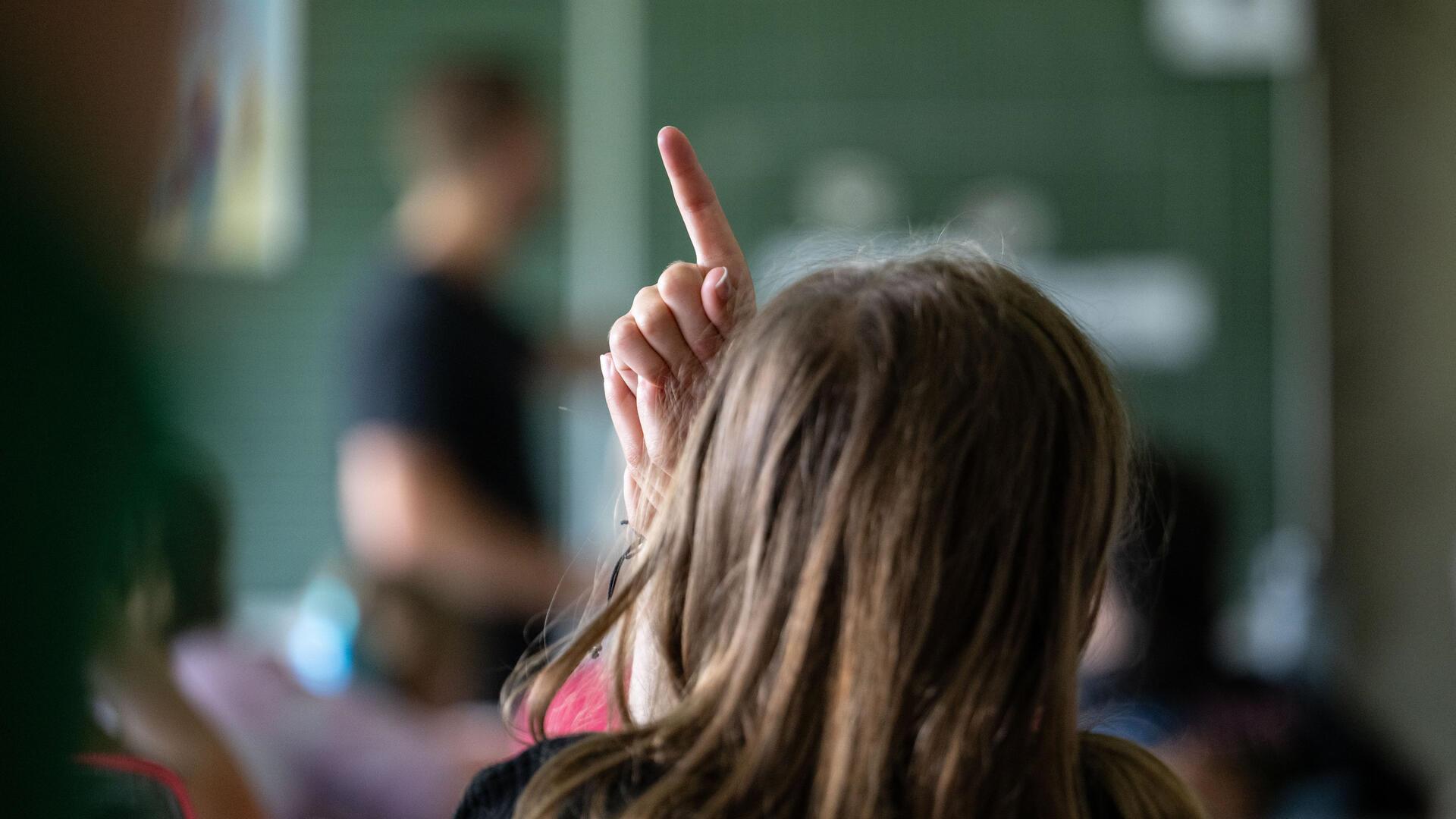 Schülerinnen und Schüler einer vierten Klasse einer Grundschule nehmen am Unterricht teil, eine Schülerin meldet sich.