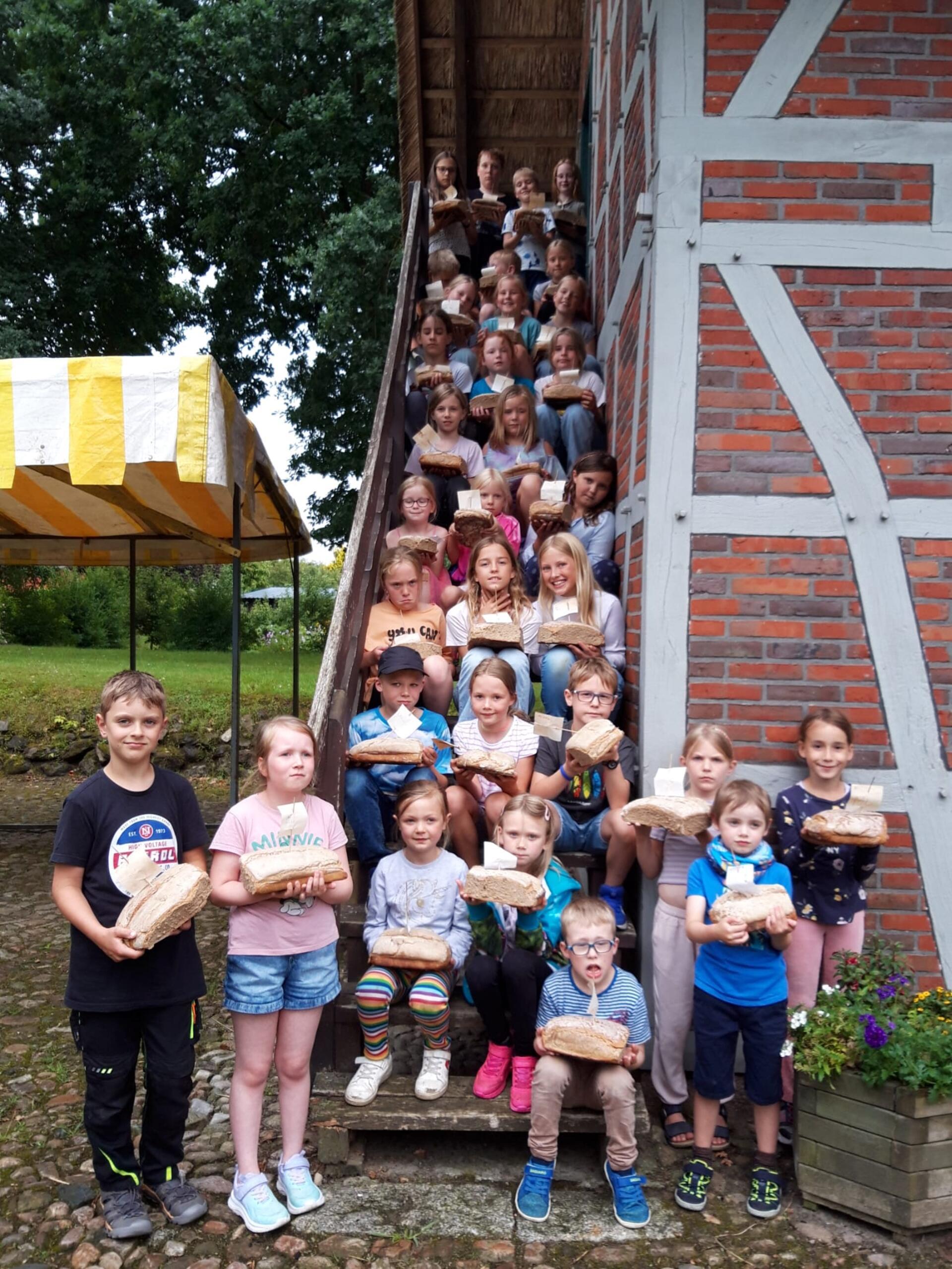 Kinder mit selbst gebackenem Brot an einem Heimathaus