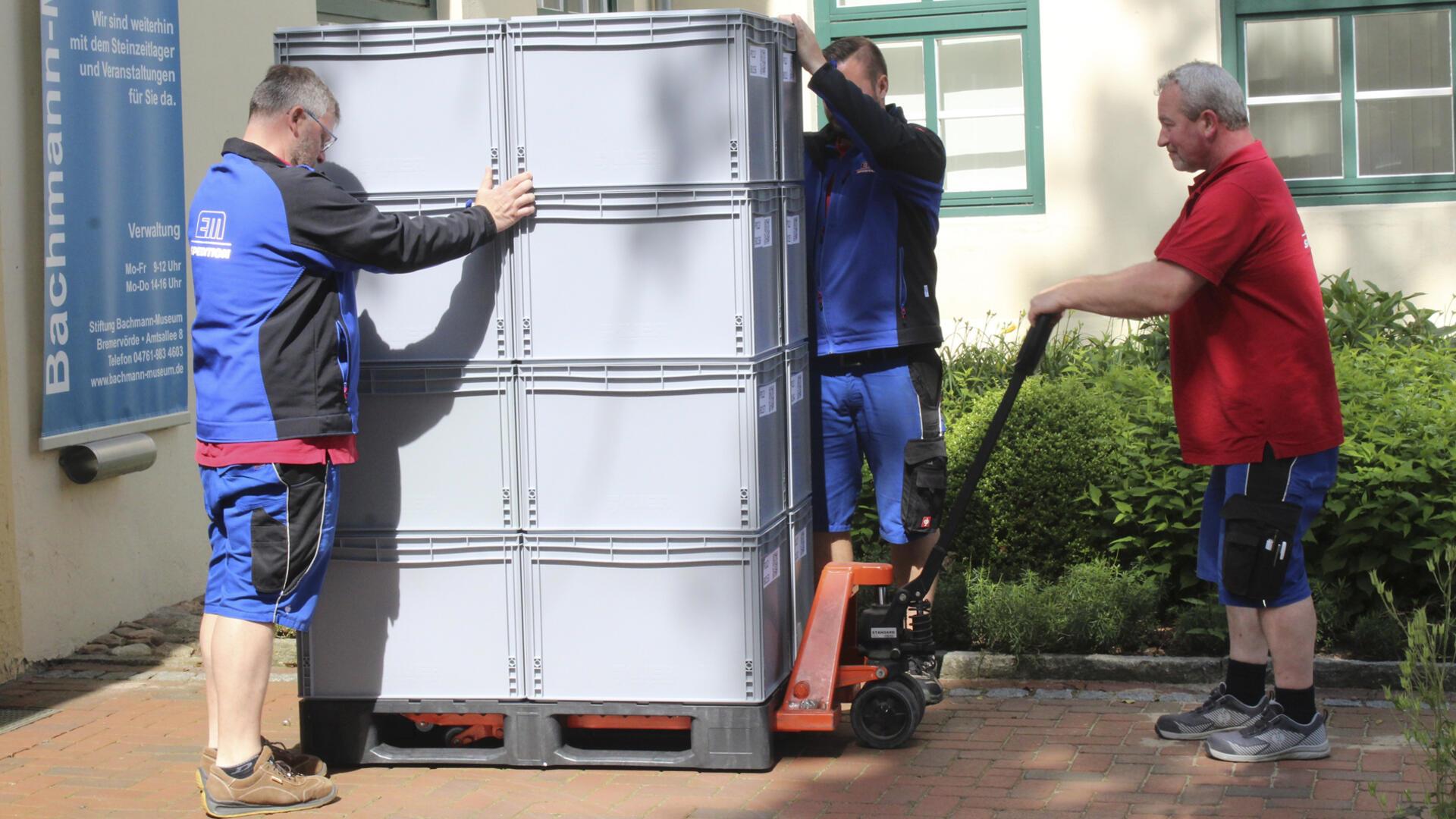 Die Mitarbeiter der Spedition Meyer transportieren die Boxen mit den Museumsobjekten vorsichtig aus dem Museumsgebäude.