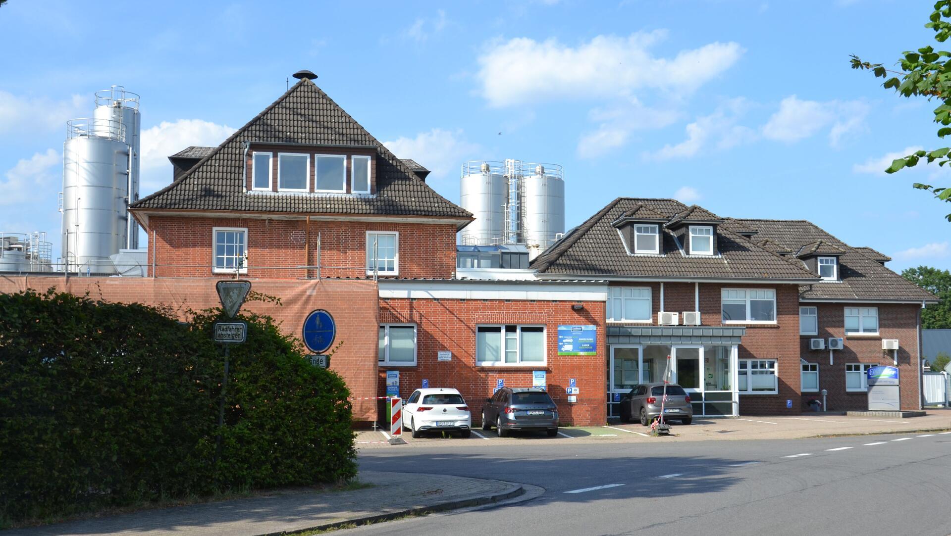 Mehrere rot geklinkerte Gebäude stehen an einer Straße.