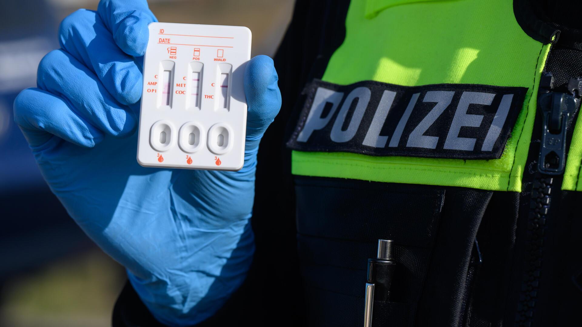 Blaue Plastikhandschuhe halten einen Drogentester aus Plastik.