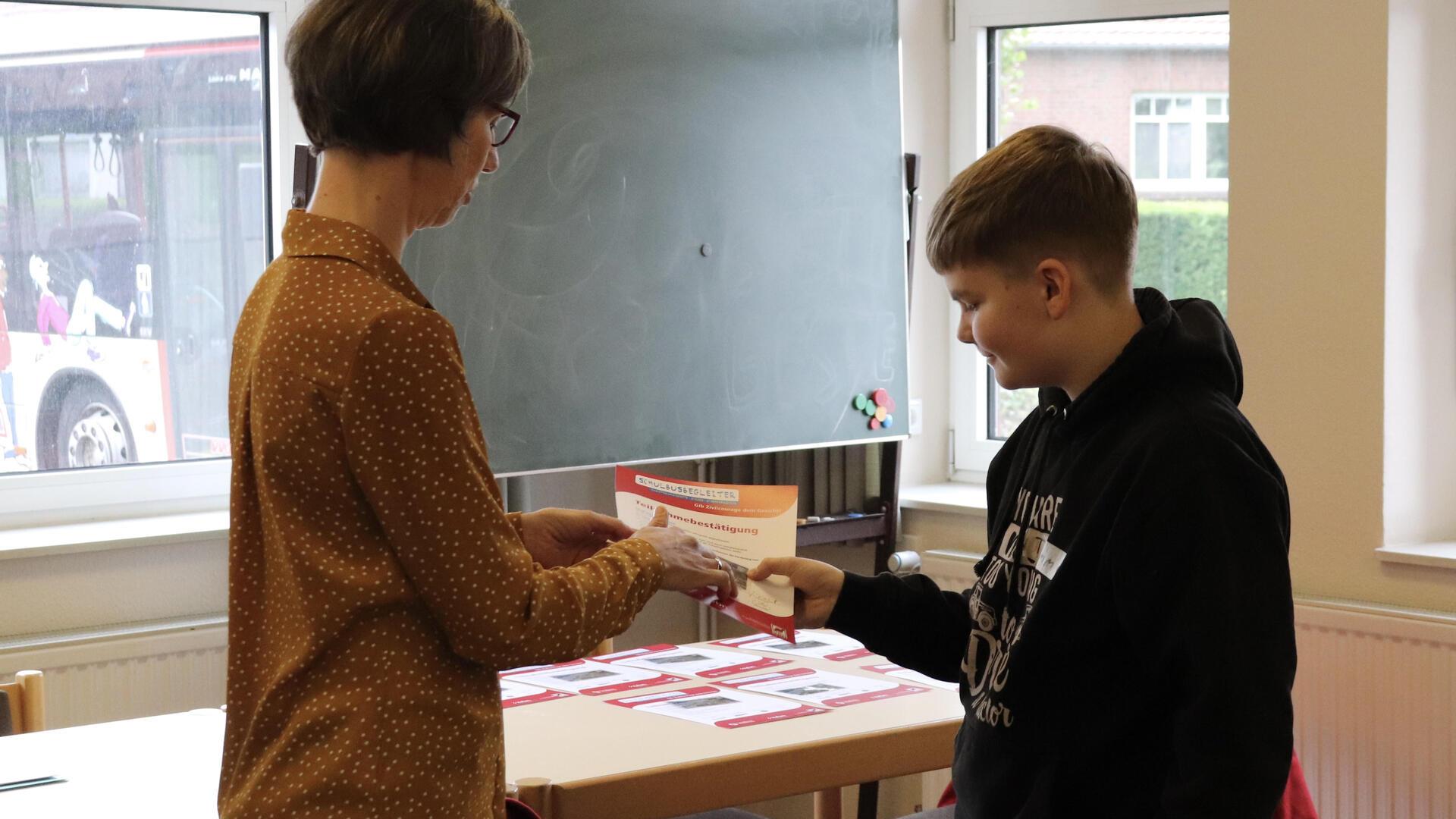 Die Projektorganisatorin Veronika Schlierf überreicht die Teilnahmebescheinigungen an die Schüler. Timm Jonas Othersen freut sich nun über seinen neuen Ruf als Buslotse.