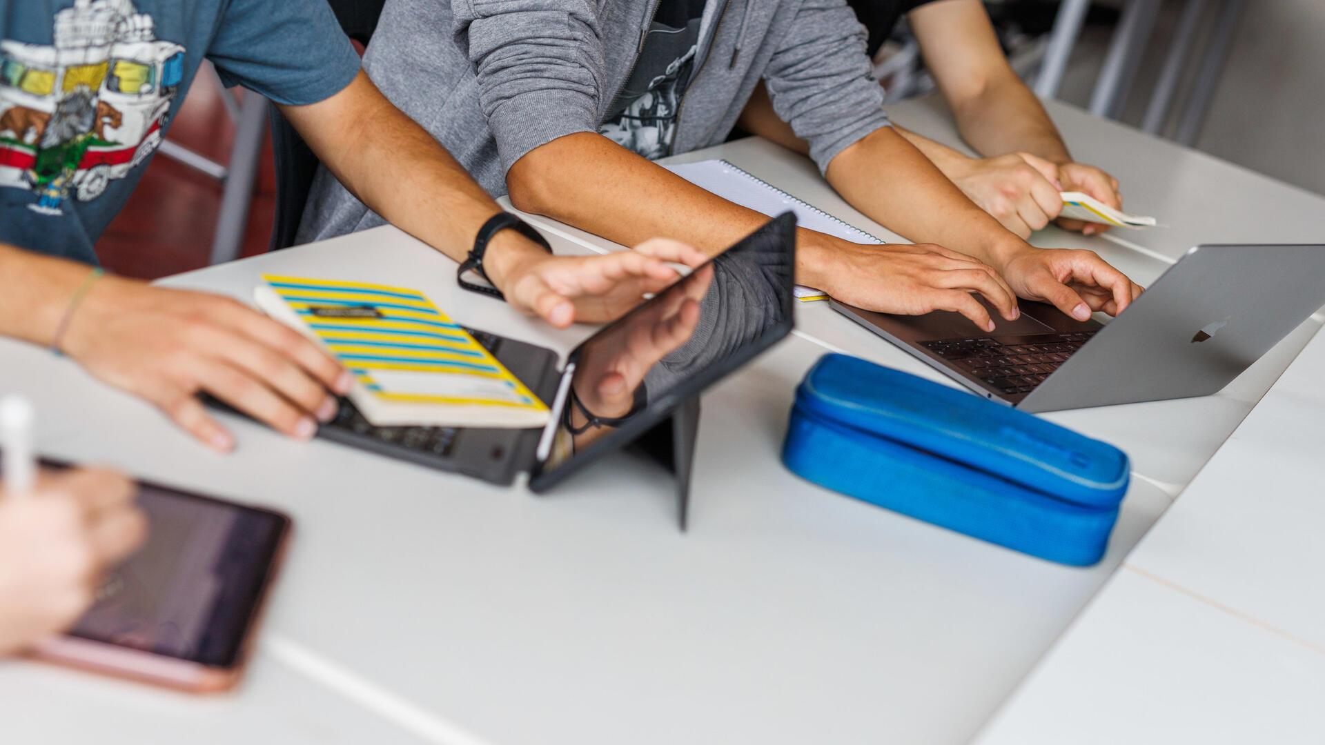 Schüler sitzen vor einem Laptop.