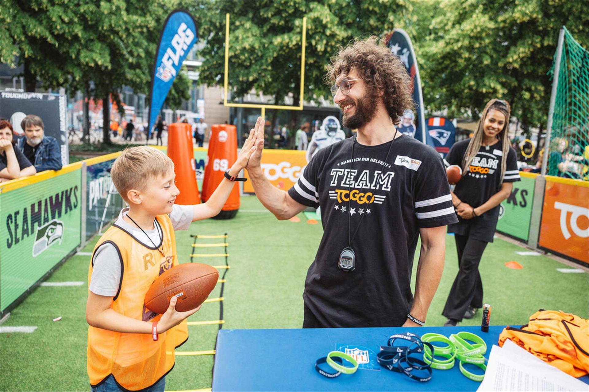 Football-Spelstation Kind klatscht mit Mann ab