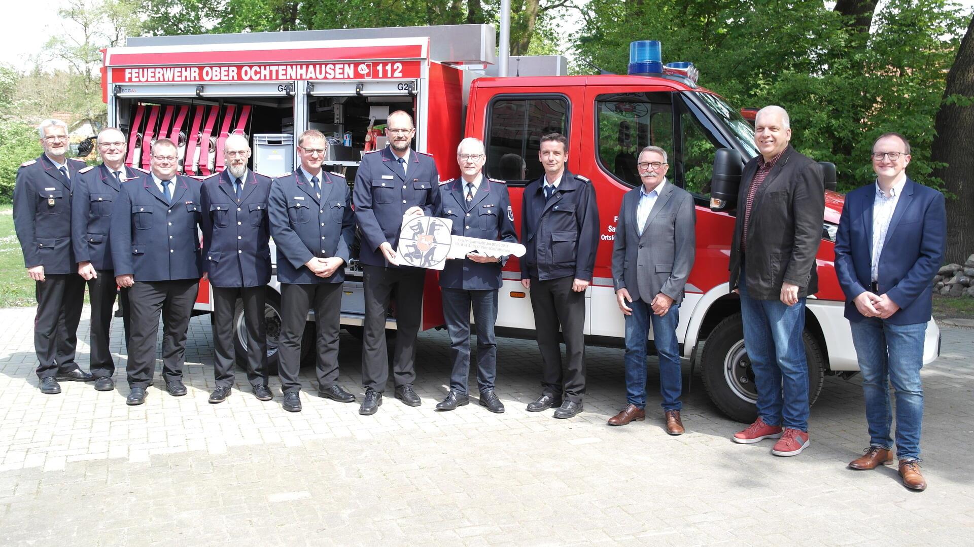 Die Verantwortlichen der Feuerwehrführung, des Feuerwehrausschusses und der Samtgemeindeverwaltung mit dem symbolischen Fahrzeugschlüssel vor dem neuen TSF-W.