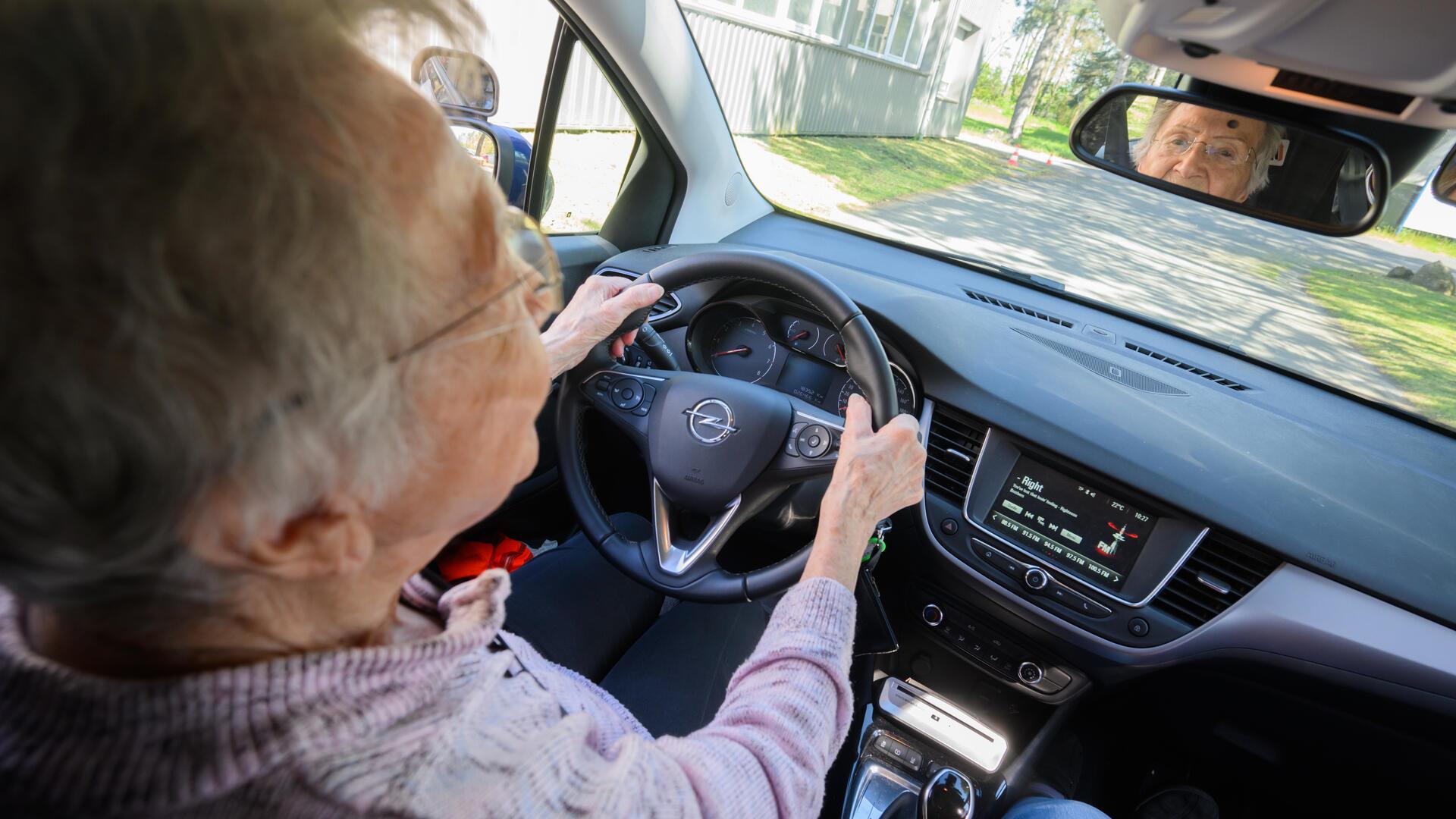 Eine Seniorin fährt Auto. 