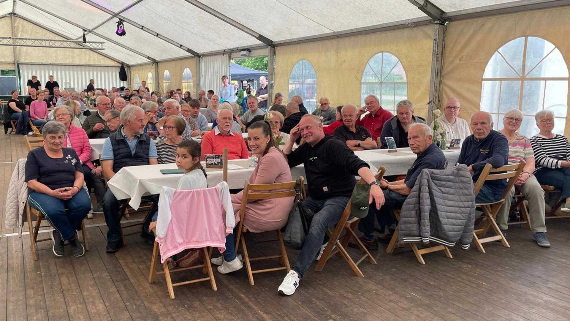 Leute im Festzelt schauen sich das Festprogramm an.  