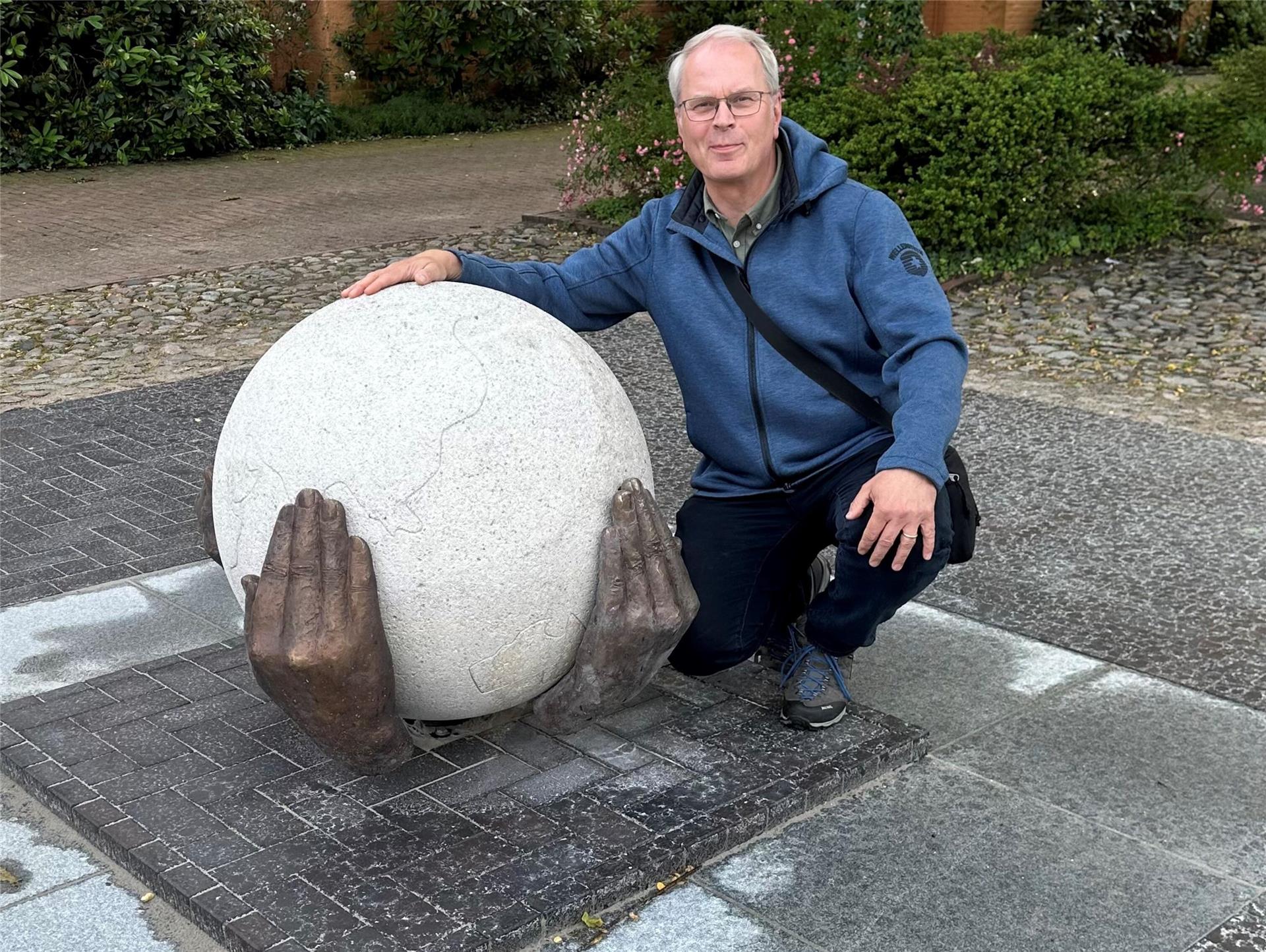 Die Weltkugel ruht in schützenden Händen: Auch Pastor Gerhard Schäfer freut sich auf die Einweihung des Friedensdenkmals vor der Kirche.