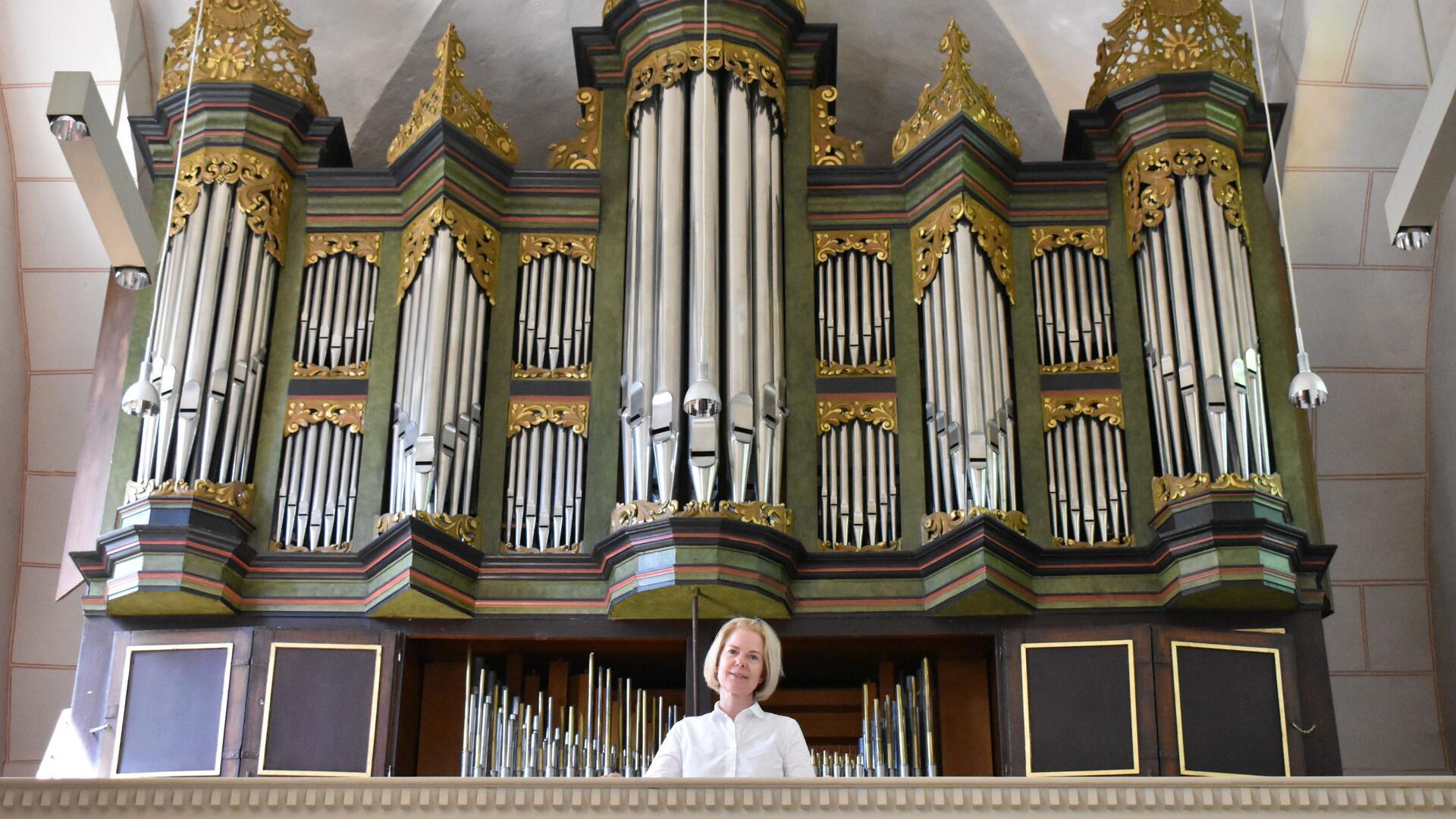 Frau mit weißer Bluse vor einer Kirchenorgel