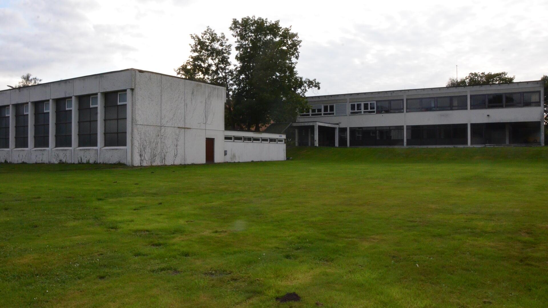 Die alte Turnhalle (links) wird abgerissen. Auf der Grünfläche im vorderen Bereich soll ein Neubau entstehen.