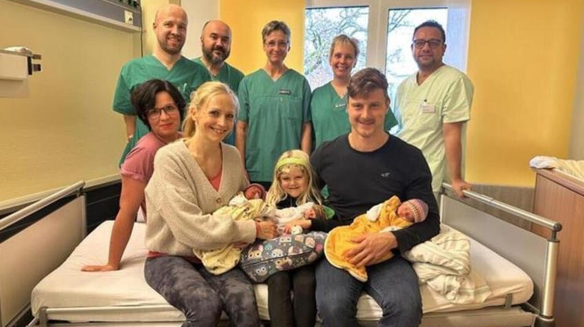 Die glückliche Familie mit ihren Drillingen, umgeben vom Team der Geburtshilfe, Kinderklinik und der Kinderintensivstation.