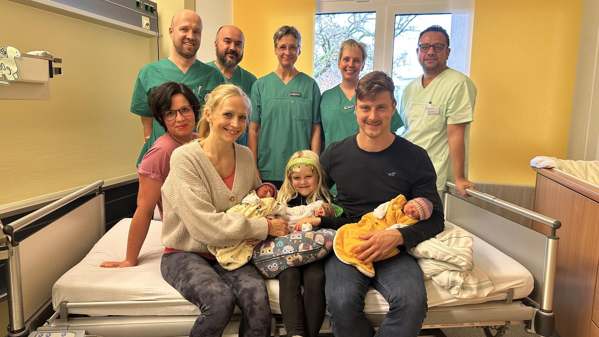 Die glückliche Familie mit ihren Drillingen, umgeben vom Team der Geburtshilfe, Kinderklinik und der Kinderintensivstation.