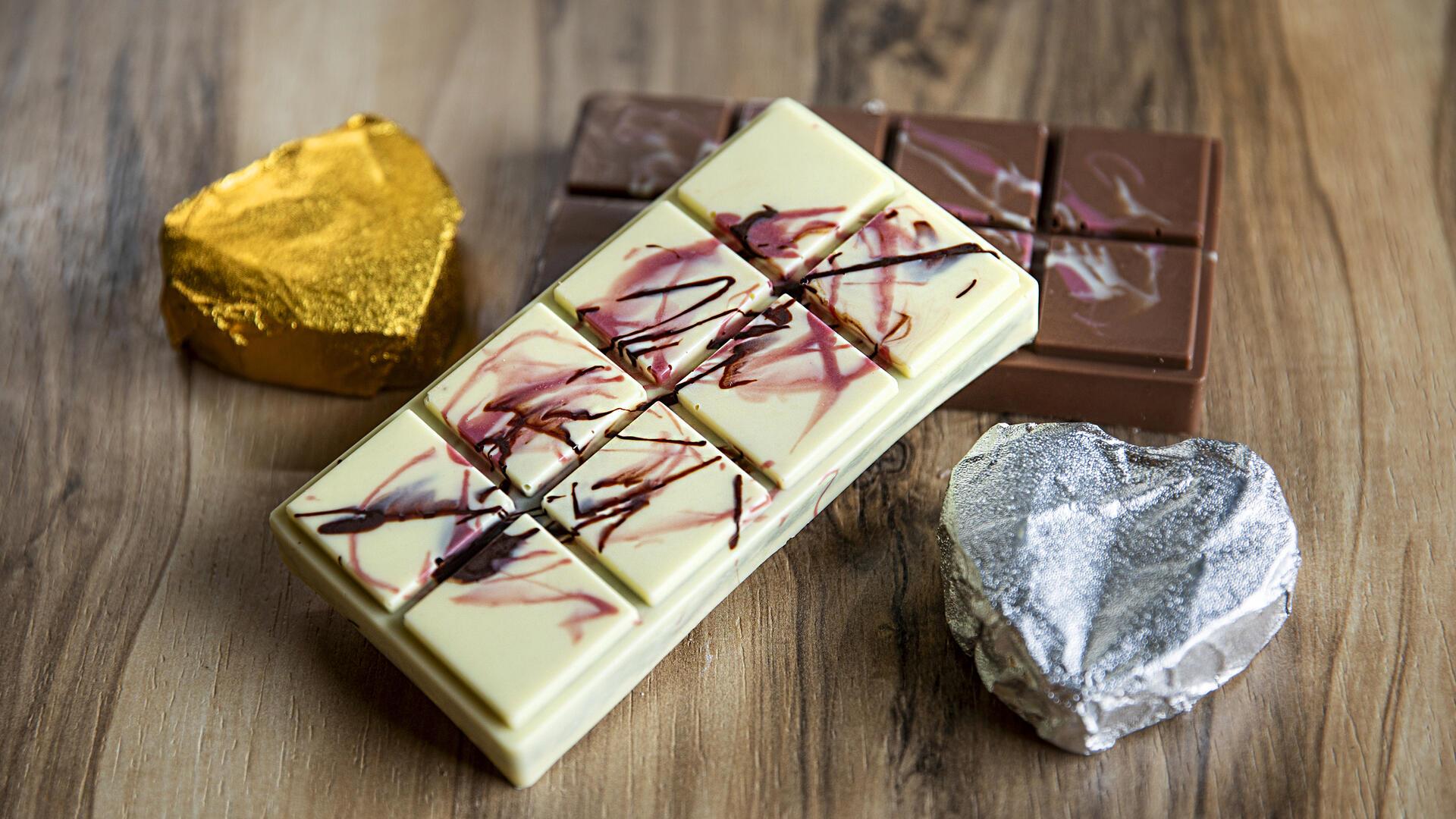 Zwei kunstvoll bemalte Tafeln Dubaischokolade und 2 in Silber- und Goldfolie verpackte Schokoherzen.