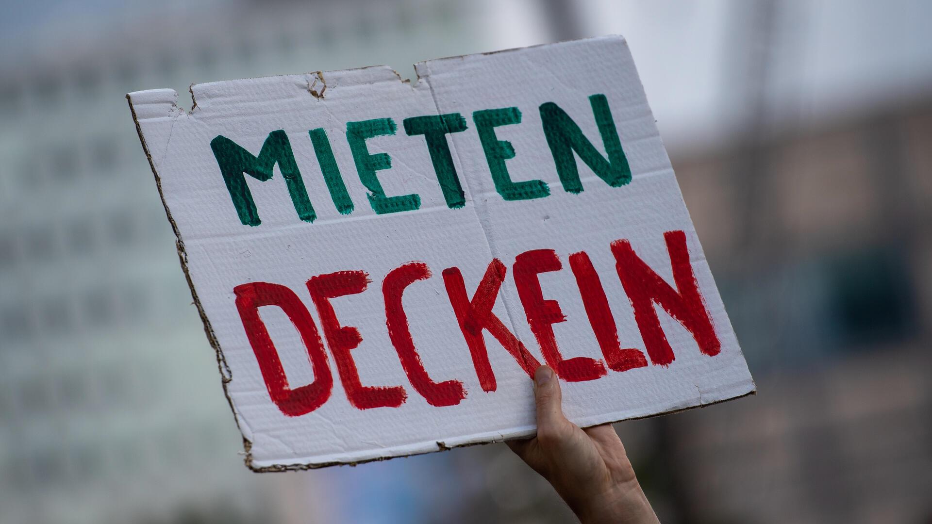 Bei einer Demonstration gegen hohe Mieten in Berlin hält ein Teilnehmer ein Plakat mit der Aufschrift "„Mieten Deckeln"