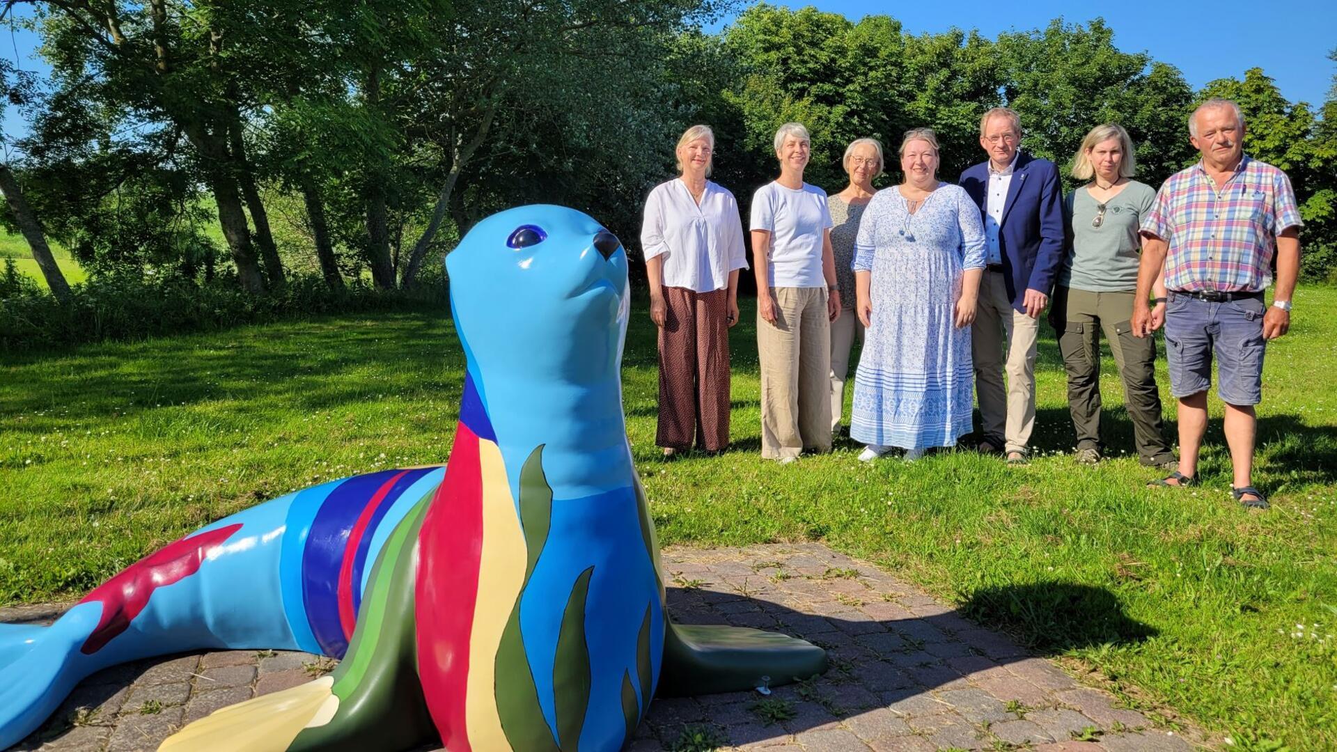 Die künstlerisch gestaltete Robbe vor dem Gästezentrum in Wremen ist ein Blickfang. Das finden die Künstlerinnen (von links) Kerstin Stöhrwohldt, Meike Mencke und Brigitte Schulten, Anke Schöning sowie der Wremer Verkehrsvereinsvorsitzende Jan-Hinrik Dircksen, Kurdirektorin Sandra Langheim und Ortsbürgermeister Hanke Pakusch.