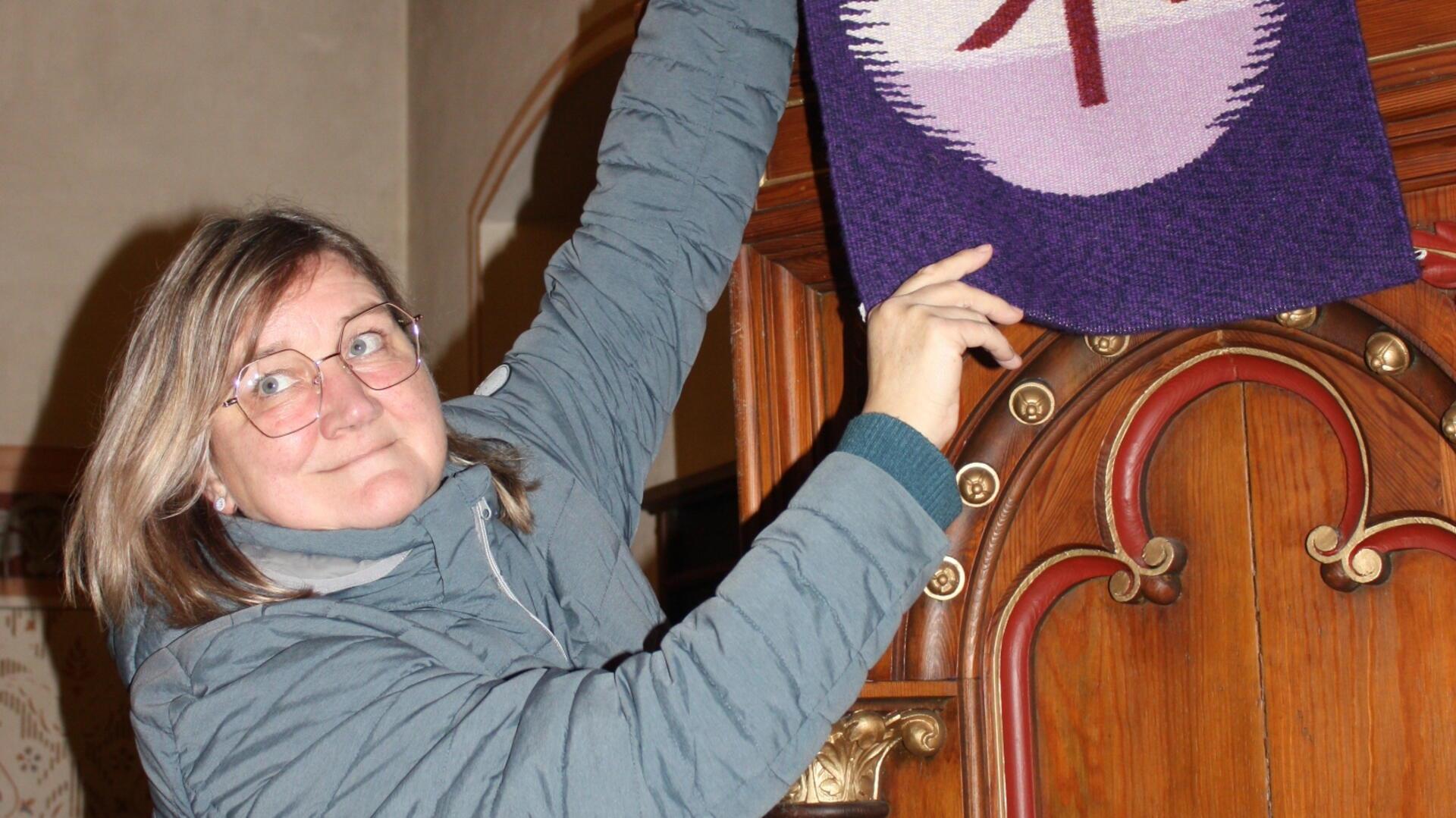 Die scheidende Küsterin Corinna Iwohn tauscht in der Hagener Martin-Luther-Kirche das Banner an der Kanzel.