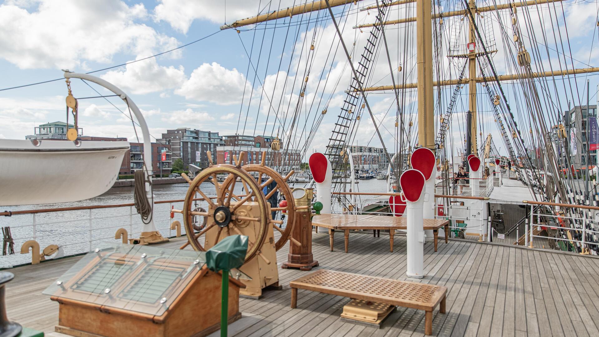 Schiffsdeck mit Steuerrad und Masten. 