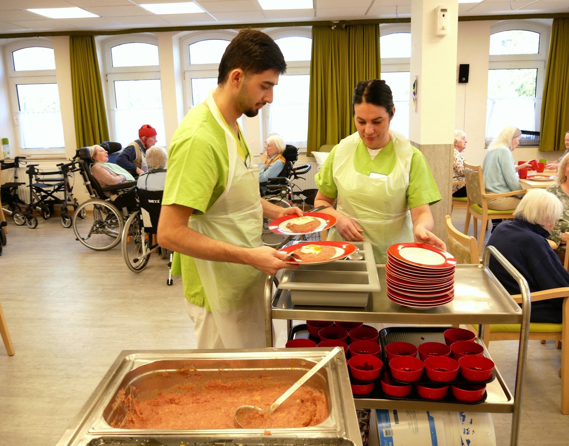 Ein Mann und eine Frau füllen Essen auf Teller.