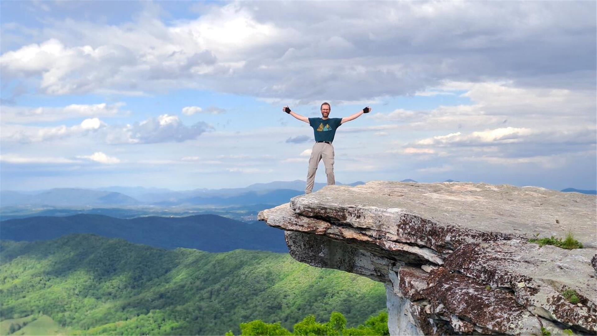 Ein Mann steht auf einem überlappenden Felsen.