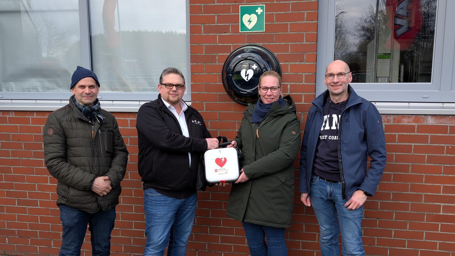 Dr. Christian Janz (links) vom Windpark-Förderverein und Unternehmer Holger Meyer (rechts) freuen sich, dass Thomas Bloch kürzlich den neuen Defibrillator an Carina Neumann vom DRK-Ortsverein überreichen konnte. Holger Meyer und der Windpark-Förderverein haben das Gerät finanziert.