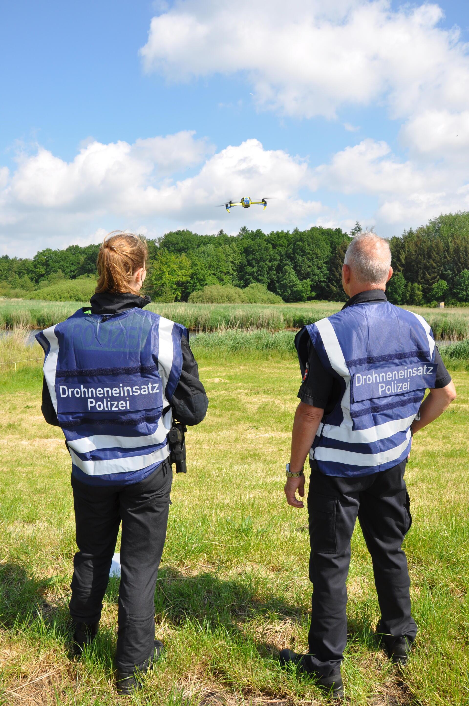 Zwei Polizisten fliegen eine Drohne.