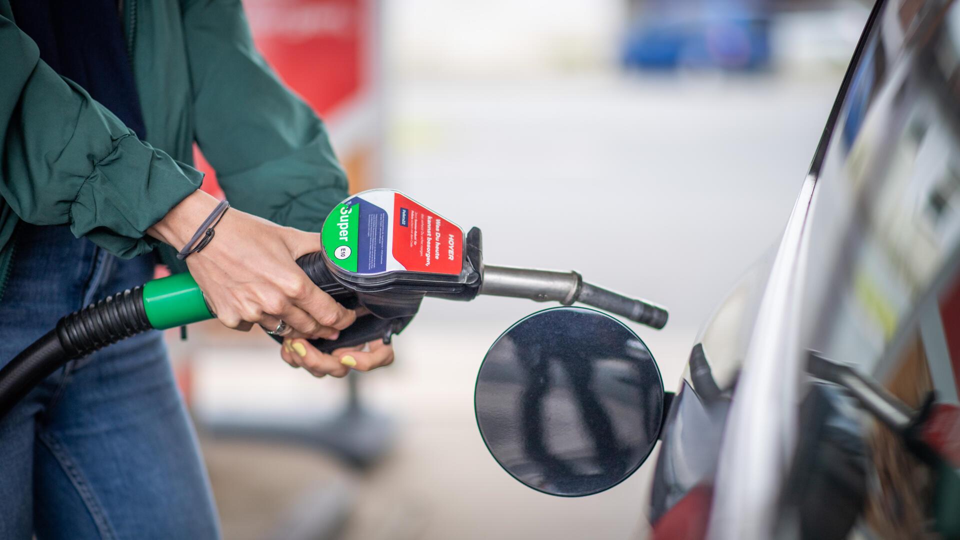 Körper einer Person im Anschnitt. Die Person ist gerade dabei, ein Auto zu tanken. 