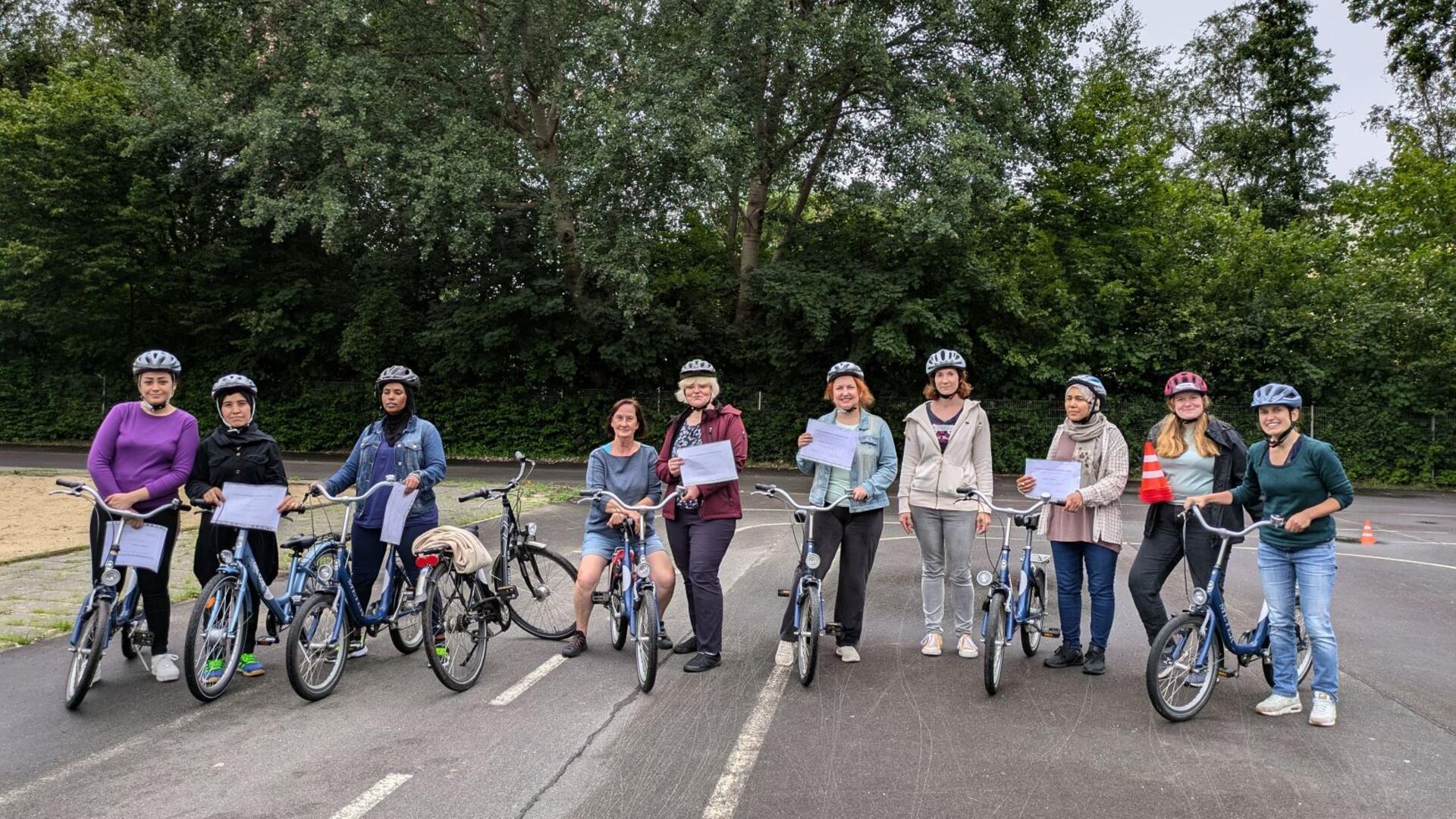 Zehn Frauen mit acht Fahrrädern stehen nebeneinander auf einem Platz für Verkehrstraining