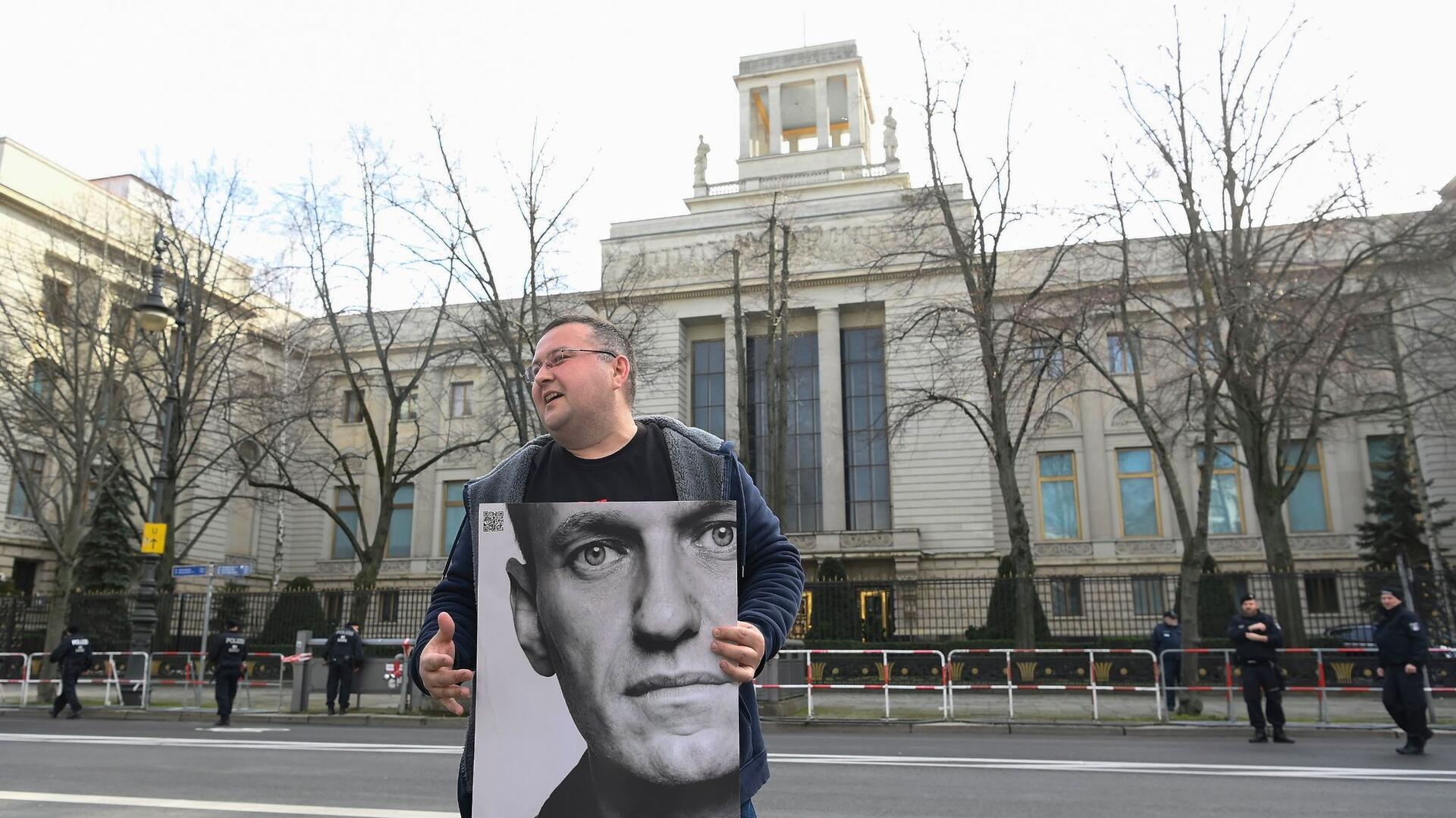 Ein Aktivist steht mit einem Plakat von Kremlkritiker Alexej Nawalny vor der russischen Botschaft in Berlin und protestiert.