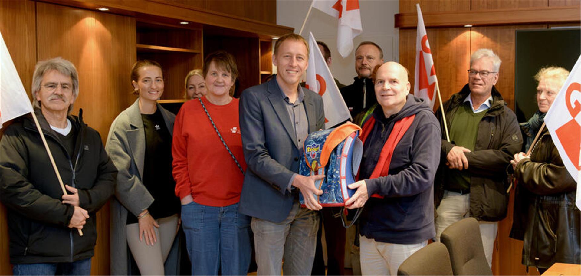 Ein Antrittsgeschenk in Form eines Schulranzens erhielt der neue Schuldezernent Hauke Hilz (Mitte) von Peer Jaschinski, Sprecher der Gewerkschaft Erziehung und Wissenschaft in Bremerhaven, und weiteren GEW-Vertretern.