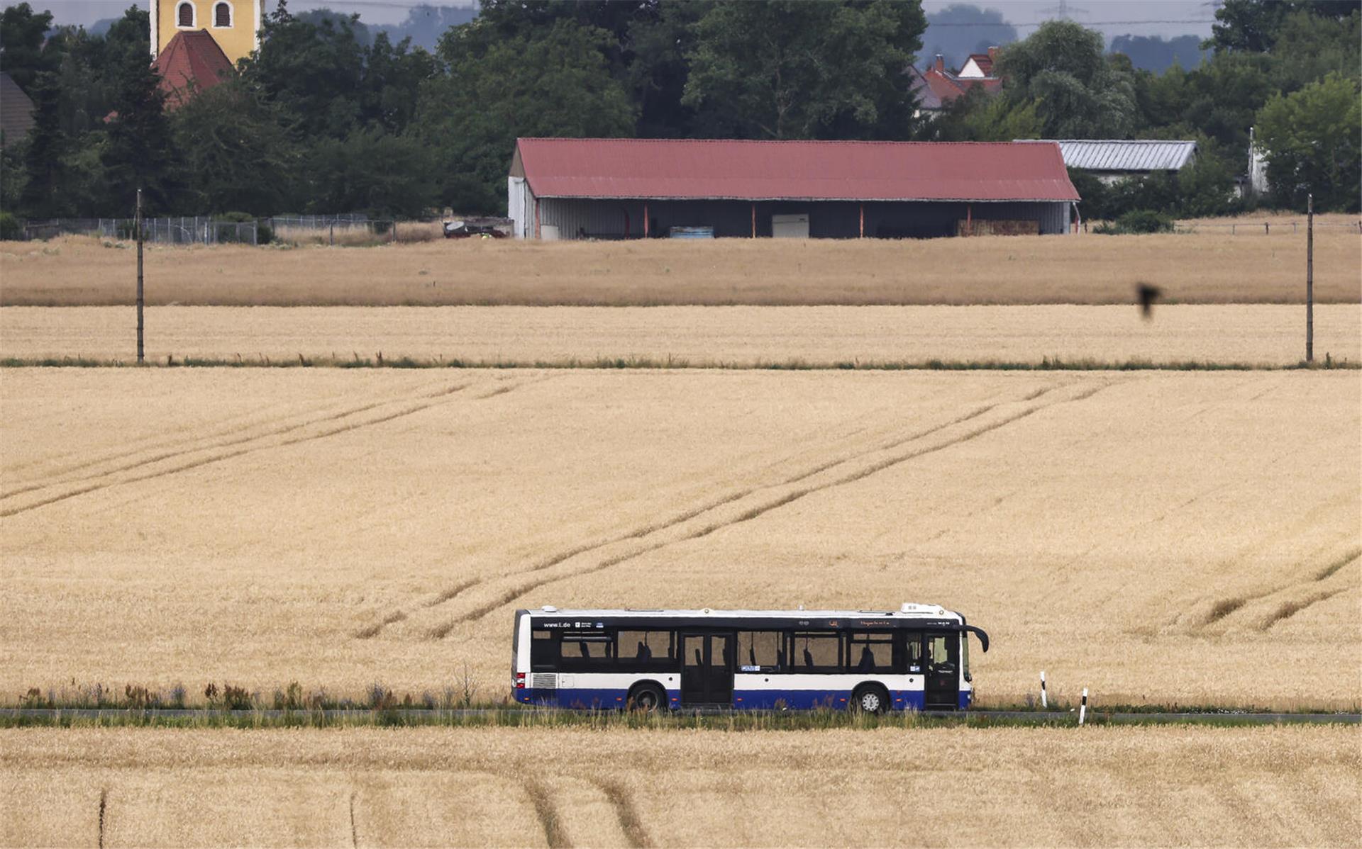 Ein Bus fährt zwischen zwei Feldern über eine Landstraße.