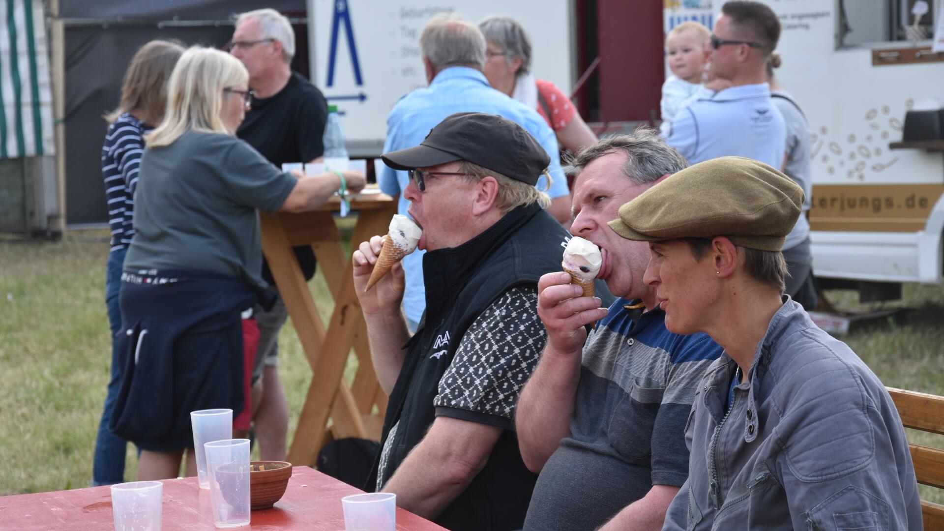 Das Foto zeigt zwei Männer, die ein Eis essen. 